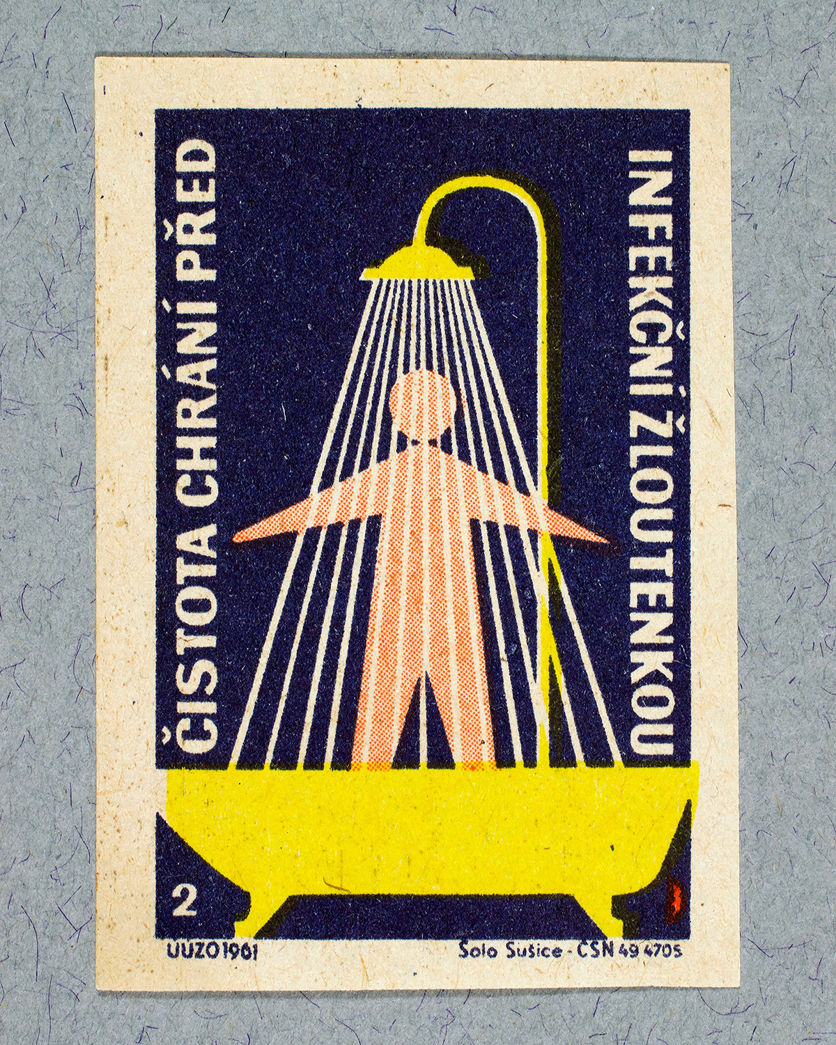 1961 Czech matchbox label by Solo Sušice showing a simple human figure standing in a yellow bath. Streams of water illustrated as clean white lines fall from a shower head. Used as a public service message promoting personal hygiene and cleanliness to prevent disease.