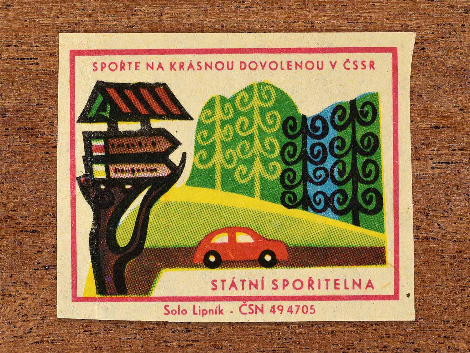 Vintage 1968 Czech matchbox label showing a roadside chalet sign and small car travelling through a countryside landscape. Produced by the Solo Lipník match factory to promote saving money for holidays in the Czechoslovak Socialist Republic.