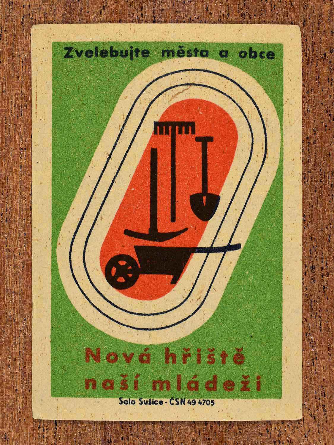 Vintage 1961 Czech matchbox label showing a sports running track loop enclosing gardening/construction tools like a wheelbarrow, rake, and shovel. Produced by the Solo Sušice match factory to promote building community sports facilities for young people.