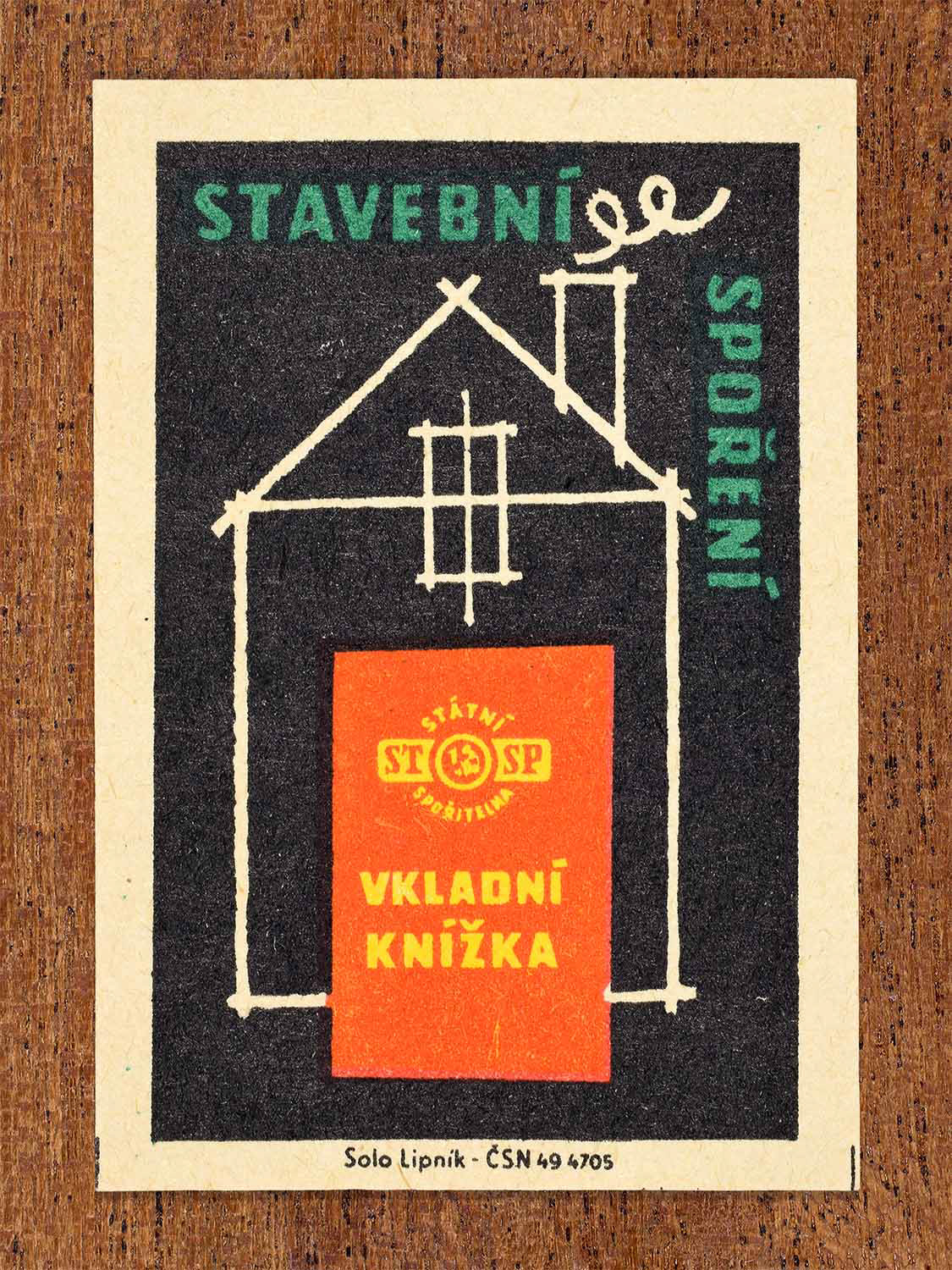 Vintage 1960 Czech matchbox label showing a house outline with a red savings passbook. Produced by the Solo Lipník match factory to promote building savings and the use of state savings accounts.