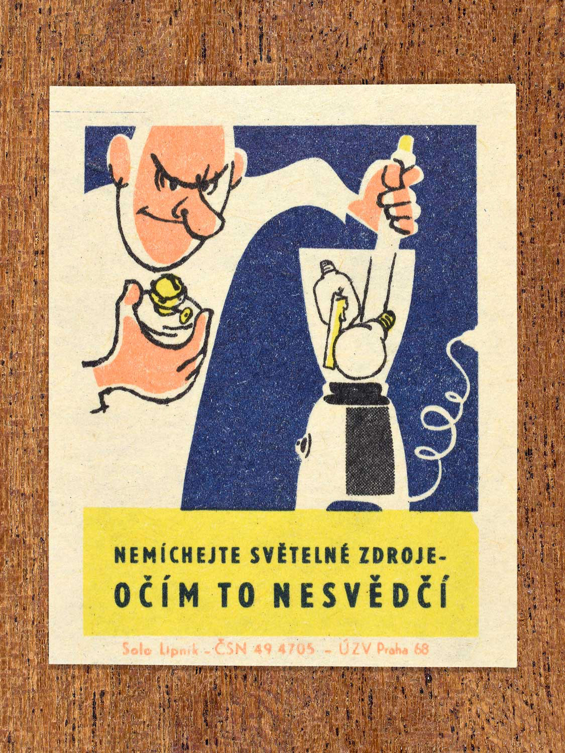 Vintage 1968 Czech matchbox label featuring a cartoon person filling an electric blender with light bulbs, on blue background. Produced by Solo Lipník match factory to promote proper lighting and maintenance for eye health and safe work practices.
