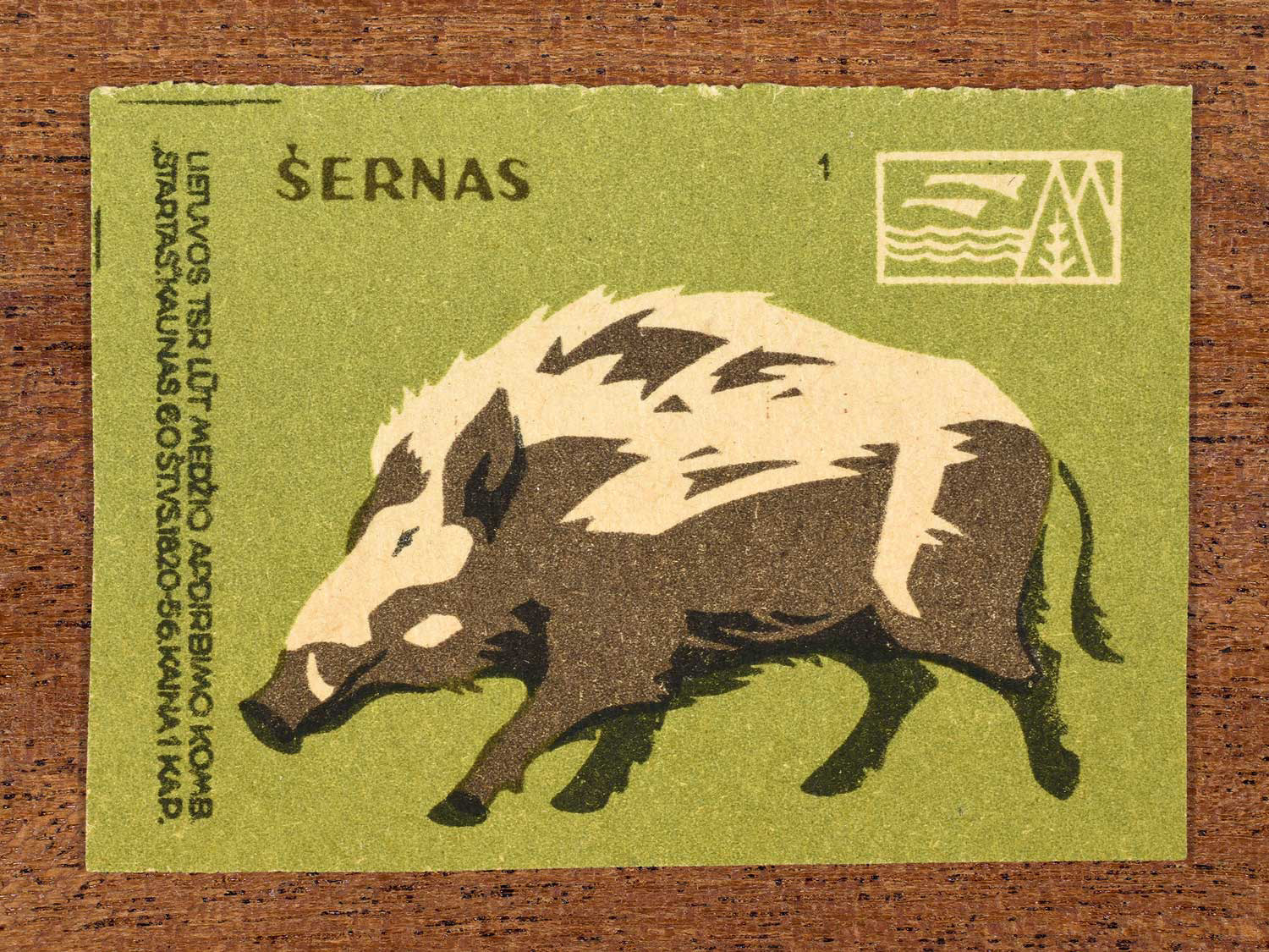 Vintage 1959 Lithuanian matchbox label showing a stylised wild boar in a dynamic running pose, on green background. Produced by the LŪT Wood Processing Combine “Startas” in Kaunas to familiarise citizens with local wildlife.