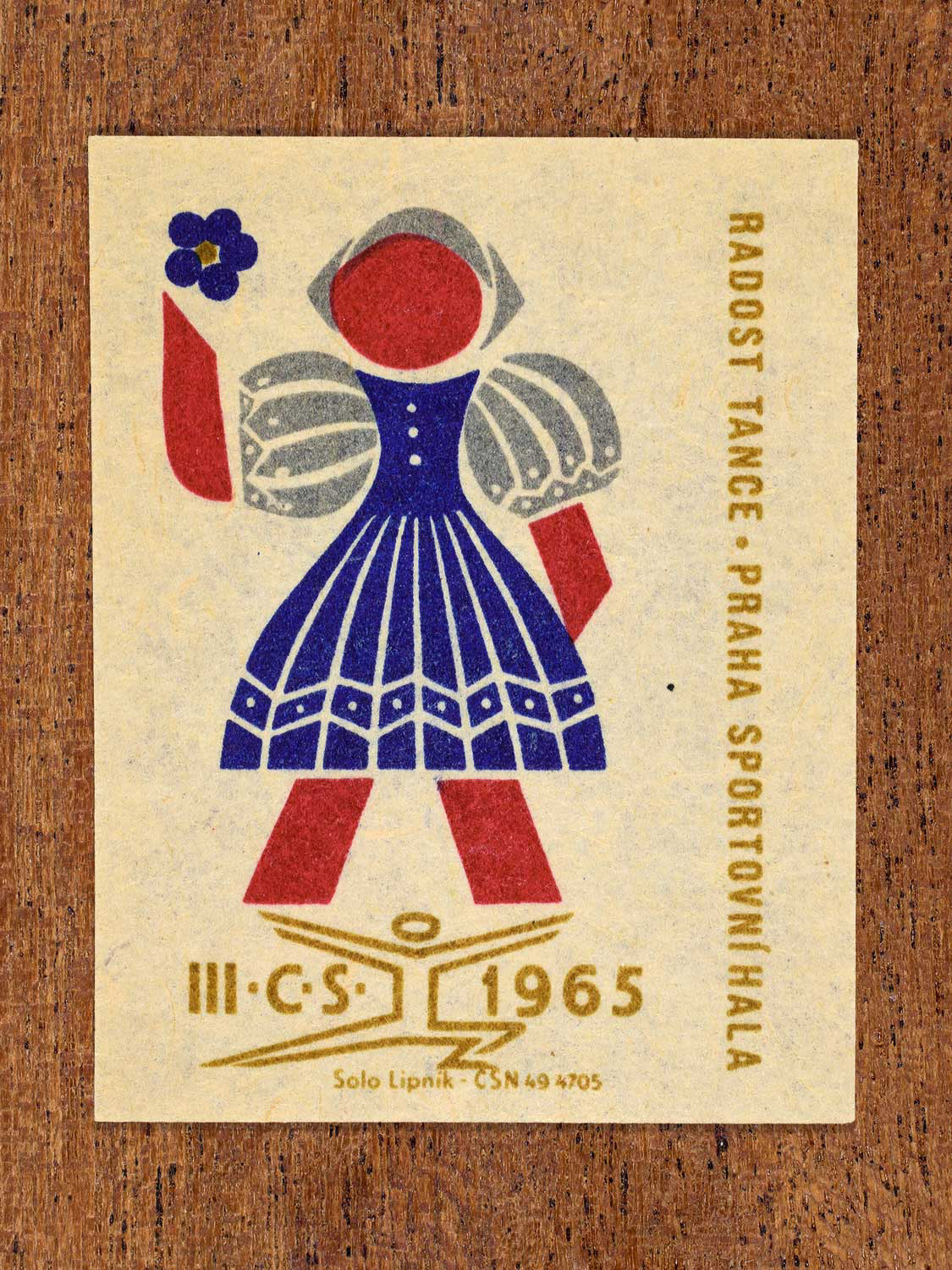 Vintage 1965 Czechoslovak matchbox label showing a stylised folk dancer in blue, red and gold colours. Produced by the Solo Lipník match factory to promote joyful social dance.