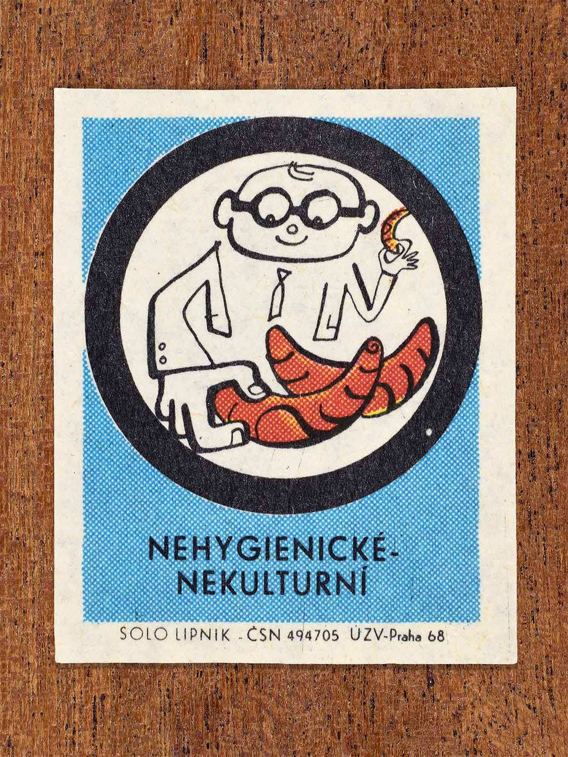 Vintage c. 1968 Czech matchbox label showing a man handling food with bare hands, framed in a circle and on a light blue background. Produced by the Solo Lipník match factory to discourage unhygienic food handling.