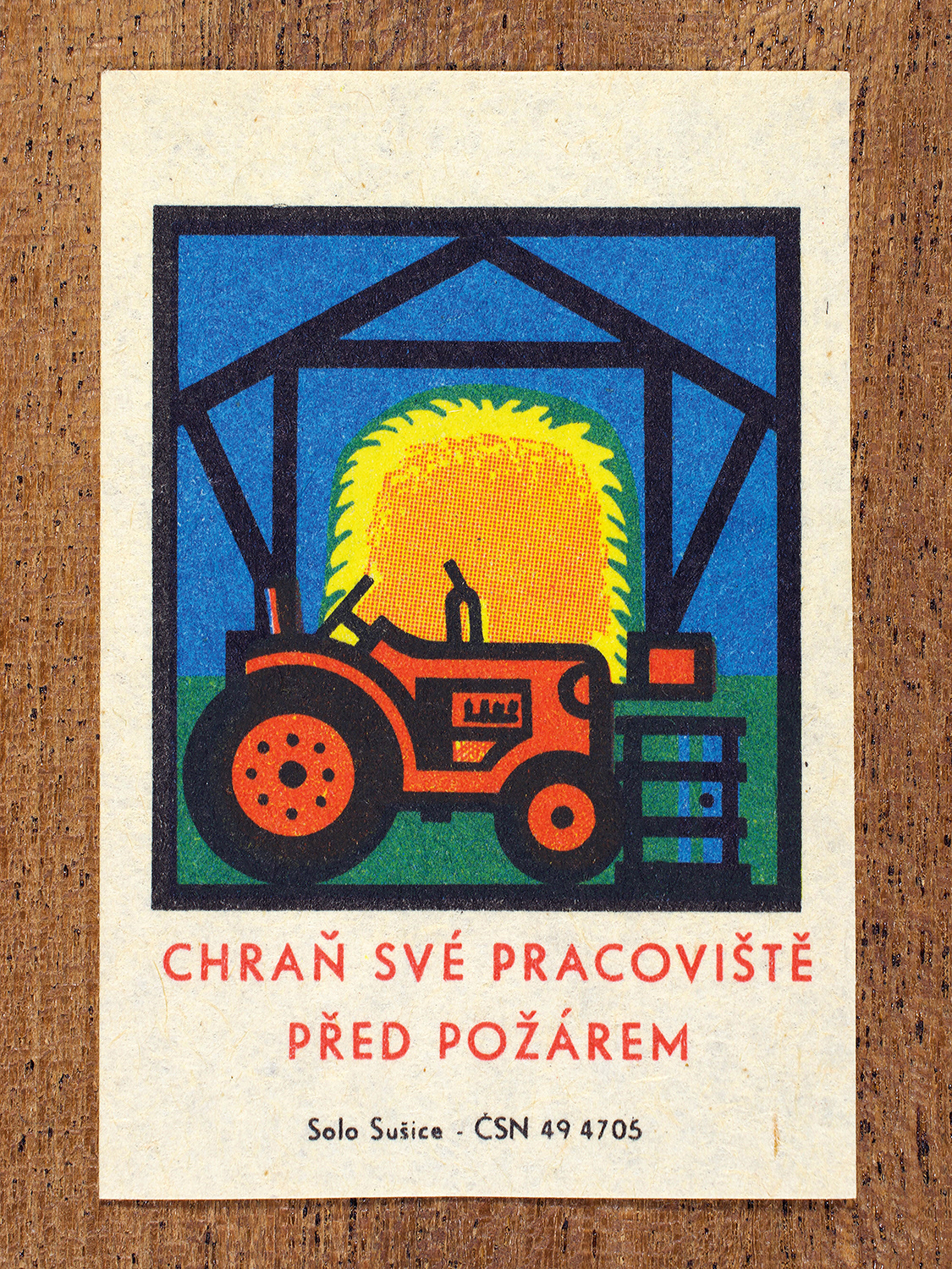 1968 Czechoslovak matchbox label by Solo Sušice showing a tractor and haystack inside a barn. Used as a public service message reminding workers to protect their barns and fields from devastating blazes. Label 2 of 10 in the Fire Hazards Series.