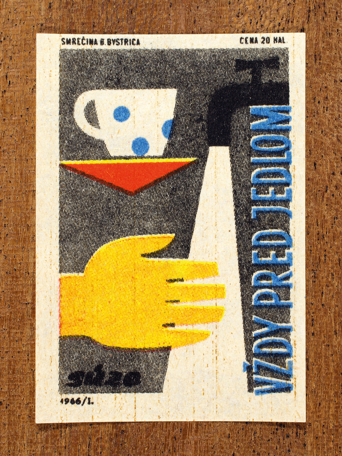 Vintage 1966 Czech matchbox label by Solo Smrečina B. Bystrica featuring a mug, and a hand under running water from a tap. It promotes handwashing before eating.