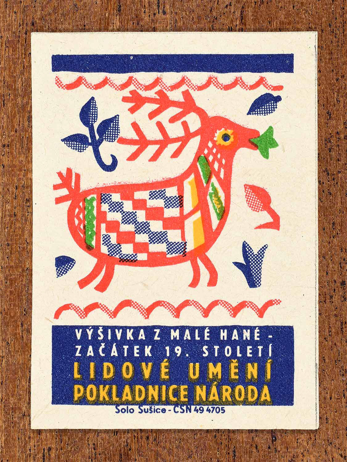 Vintage 1964 Czech matchbox label showing a stylised stag with geometric patterning in red, blue and green. Produced by the Solo Sušice match factory to present traditional embroidery from the Malá Haná region.