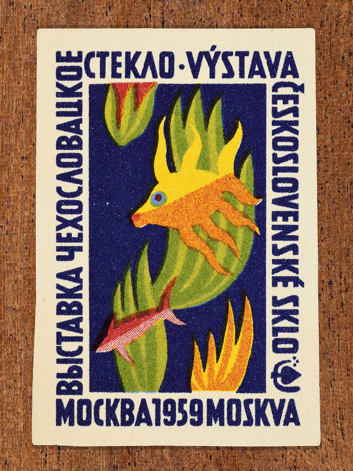 Mid-century modern Eastern Bloc illustration on a 1959 Czechoslovak matchbox label featuring an underwater scene on a dark blue background. Designed to promote an international glass exhibition in Moscow by an unknown factory.