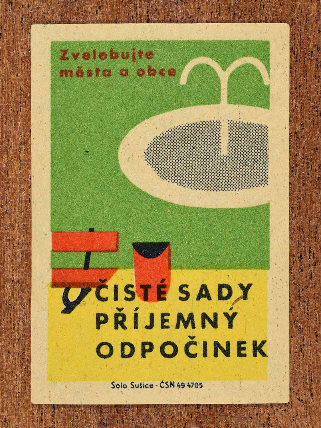 Vintage 1961 Czech matchbox label showing a park landscape featuring a water fountain, a red park bench, and a trash bin. Produced by the Solo Sušice match factory to promote clean public parks for community relaxation.