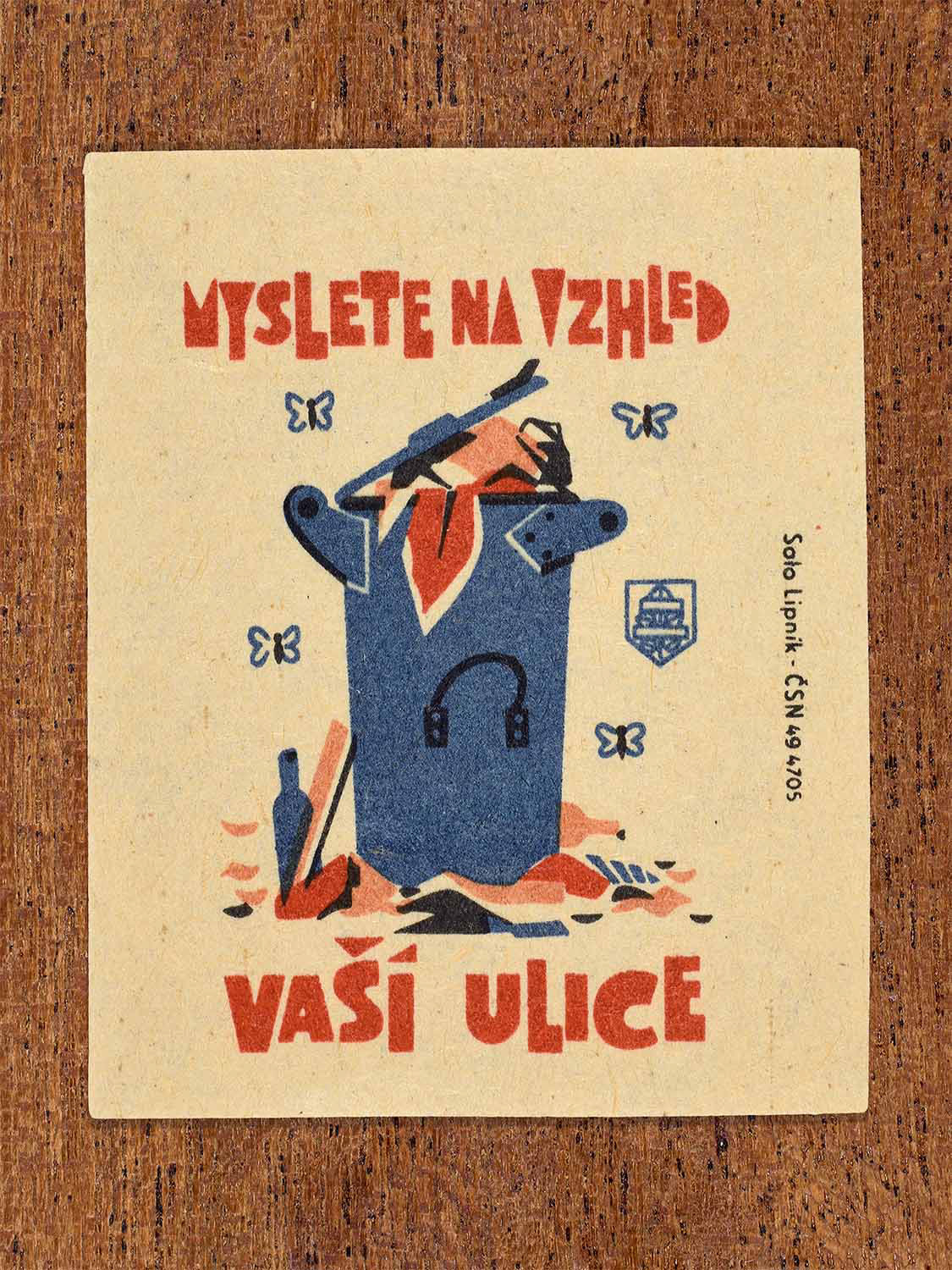 Vintage 1964 Czech matchbox label showing a public litter bin overflowing with rubbish, in blue and red colours. Produced by the Solo Lipník match factory to encourage care for the appearance of public streets.