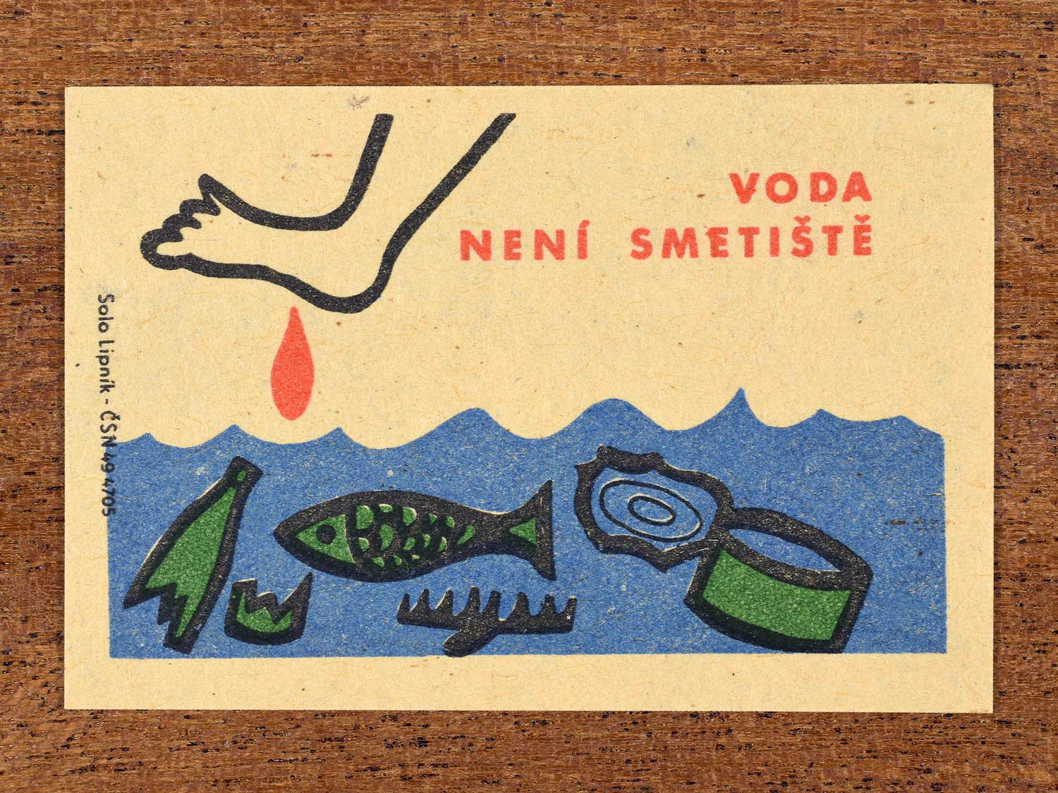 Vintage c. 1963 Czech matchbox label showing rubbish floating in water as a foot steps in, in green, red and black colours. Produced by Solo Lipník match factory warning that water is not a dumping site.