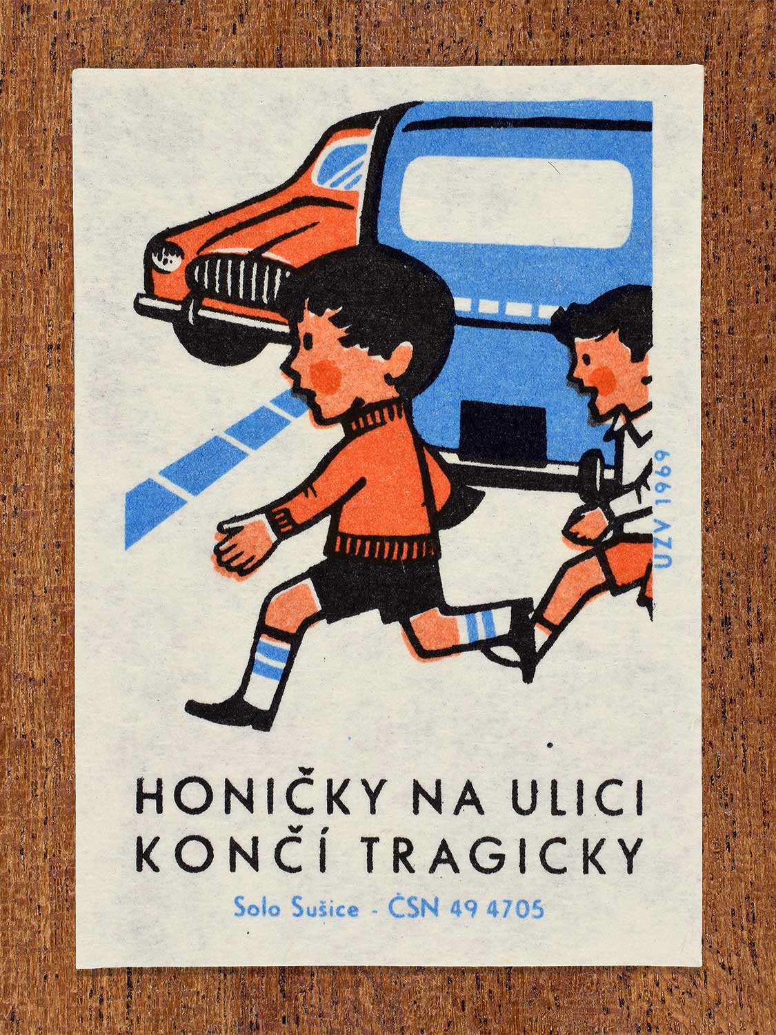 Vintage 1969 Czech matchbox label showing two young boys running and chasing each other blindly into the path of an oncoming red car. Produced by the Solo Sušice match factory to promote pedestrian awareness and prevent tragic street accidents.
