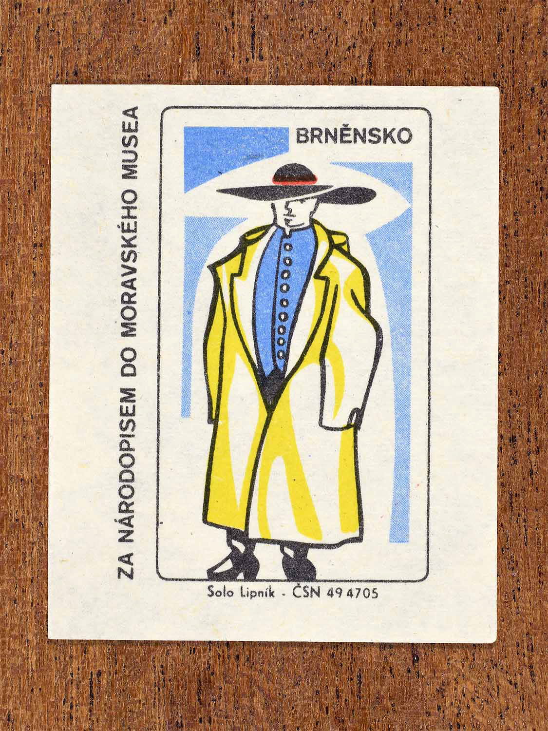 Vintage c. 1968 Czech matchbox label showing a male folk costume from the Brno region in yellow, blue and black. Produced by the Solo Lipník match factory to promote ethnography and traditional Moravian regional dress through the Moravian Museum.