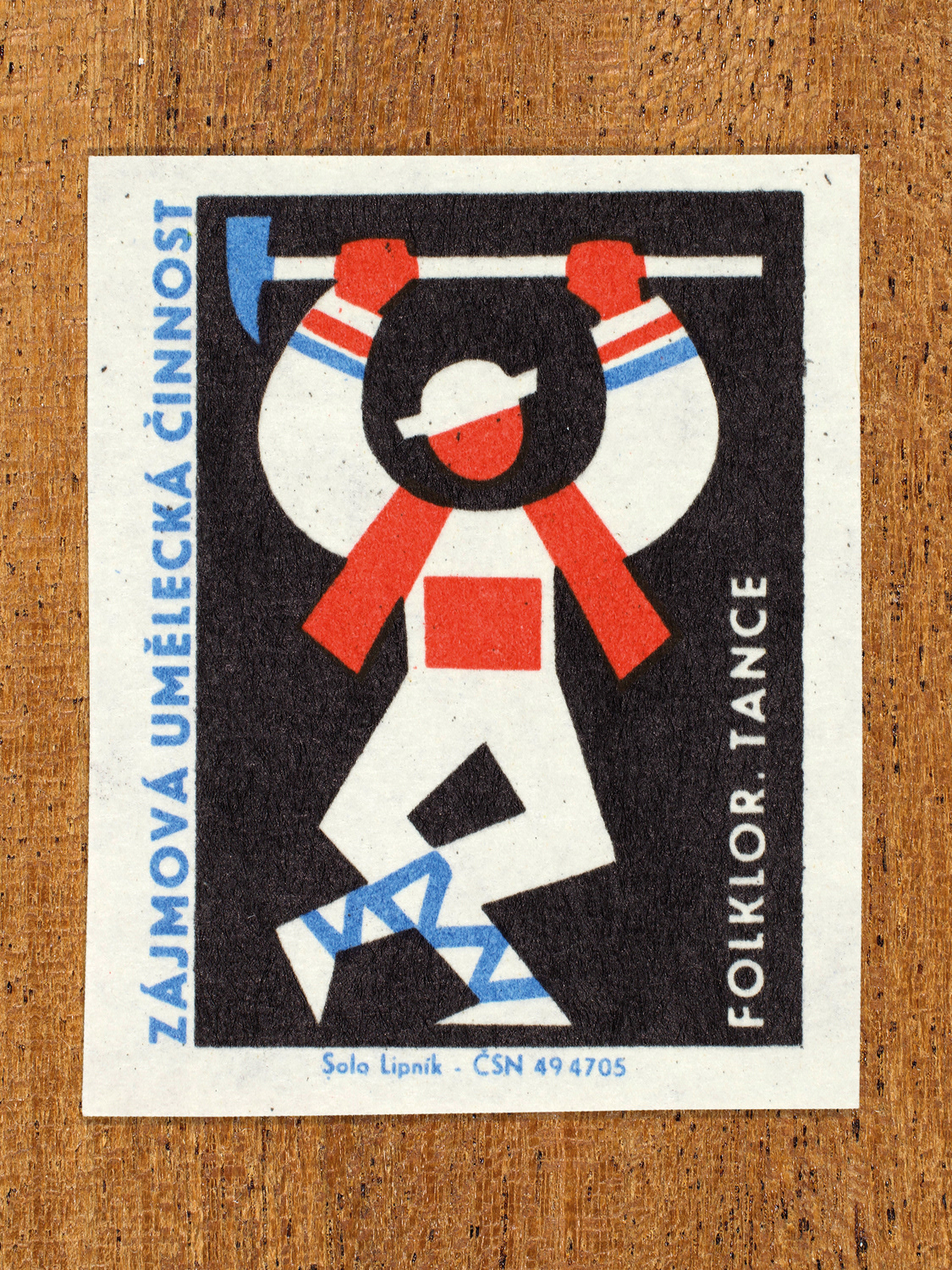 Vintage 1969 Czech matchbox label showing a stylised folk dancer with raised arms and traditional clothing, in blue, red and black colours. Produced by the Solo Lipník match factory to promote state-organised art groups in Czechoslovakia.