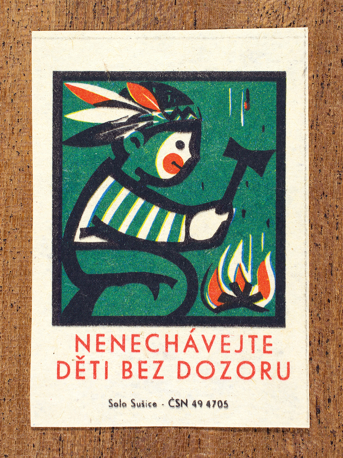 1968 Czechoslovak matchbox label by Solo Sušice showing a child playing near fire on a green background. Used as a public service message reminding parents not to leave children unsupervised near fire. Label 6 of 10 in the Fire Hazards Series.