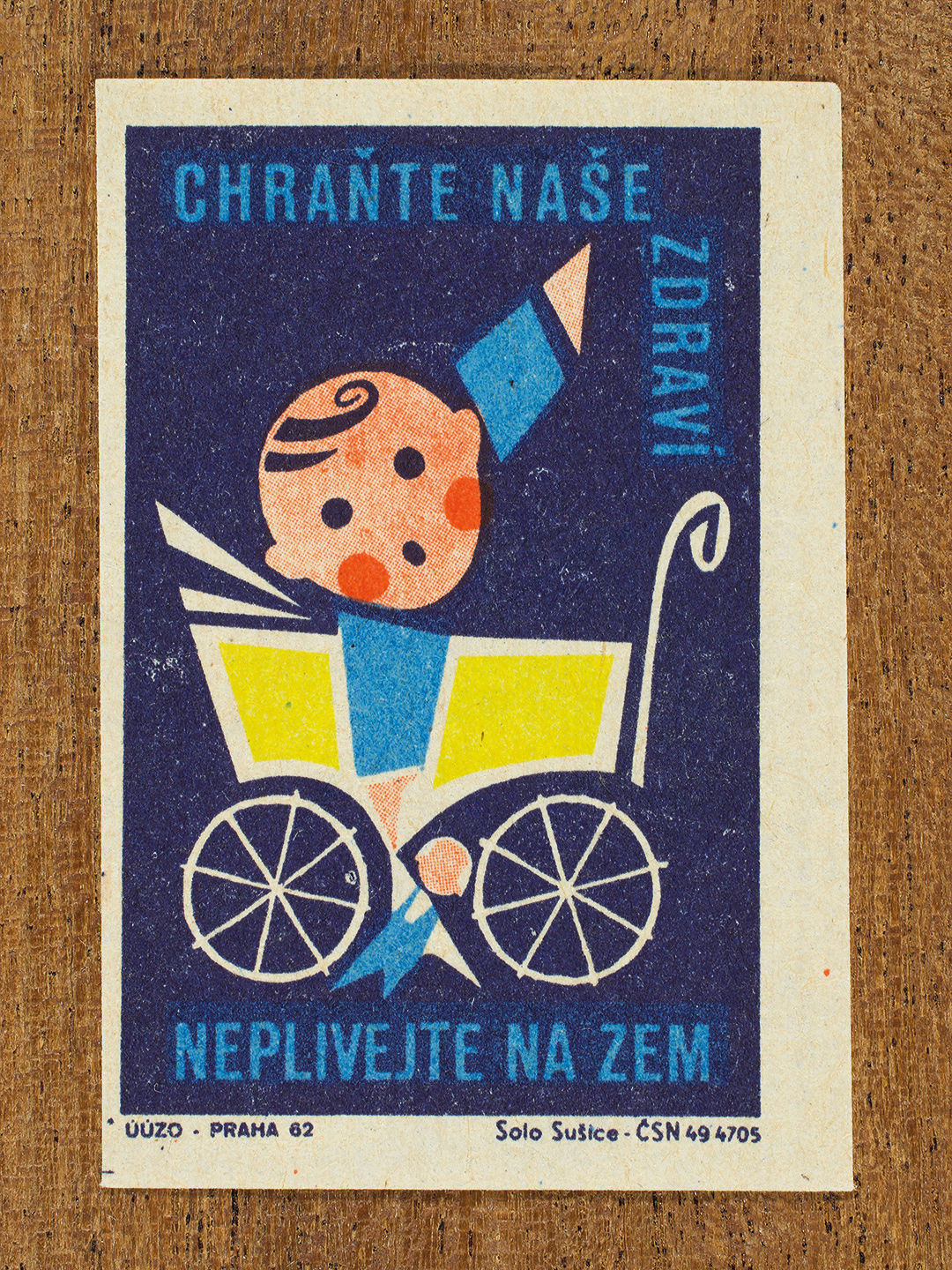 Vintage 1962 Czech matchbox label by Solo Sušice featuring a baby in a pram pointing upwards. Part of the 'Protect Health' series urging citizens not to spread germs through spitting, and to protect the health of children.