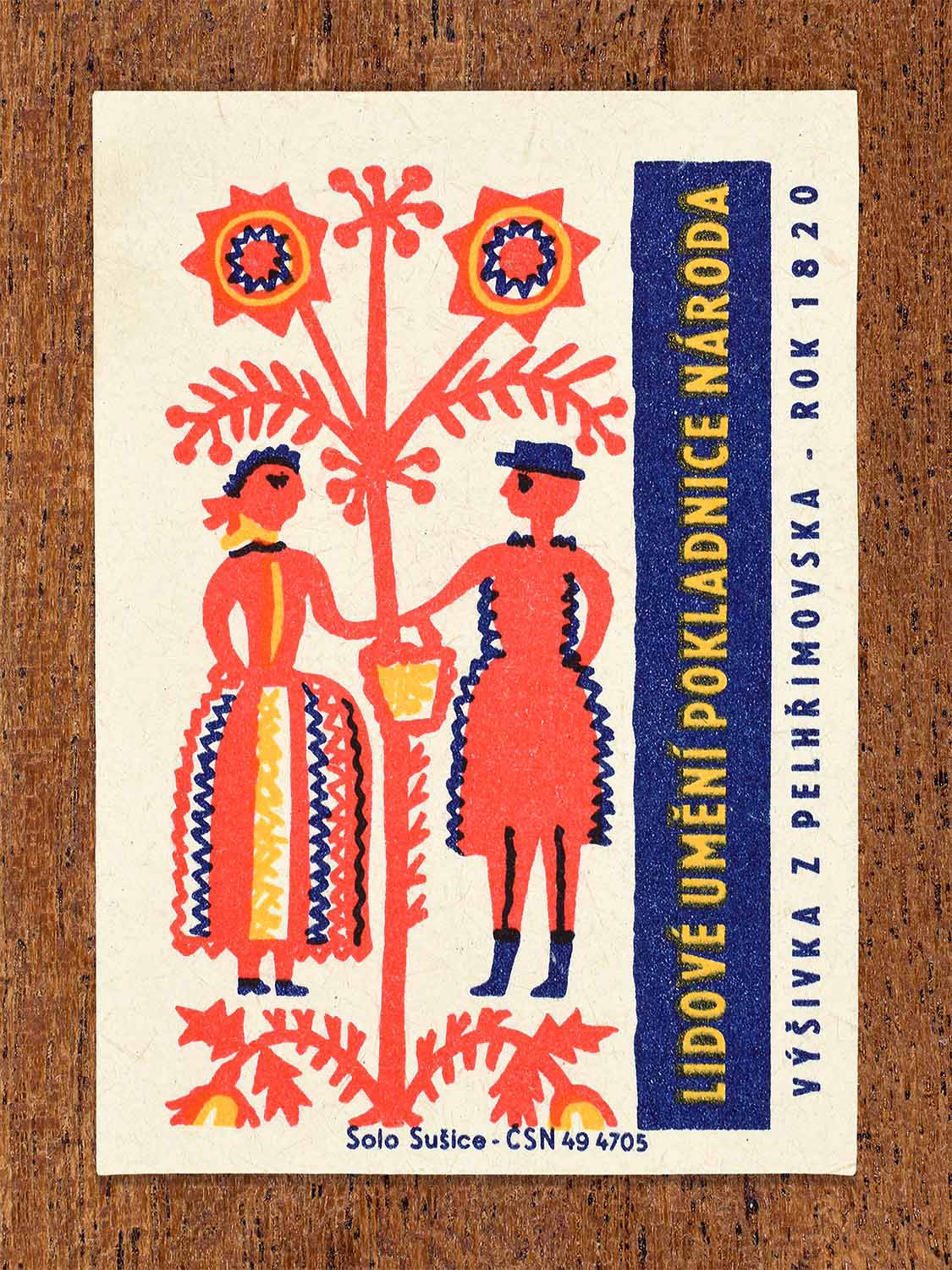 Vintage 1964 Czech matchbox label showing two stylised folk figures beneath a floral tree motif. Produced by the Solo Sušice match factory highlighting Pelhřimov regional embroidery.