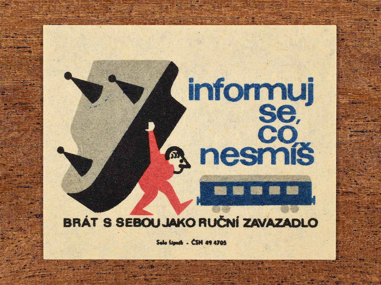 Vintage c. 1964 Czech matchbox label showing a man carrying a piano onto a train as hand luggage, illustrated in blue, red and black. Produced by the Solo Lipník match factory to inform passengers about restricted hand luggage items.