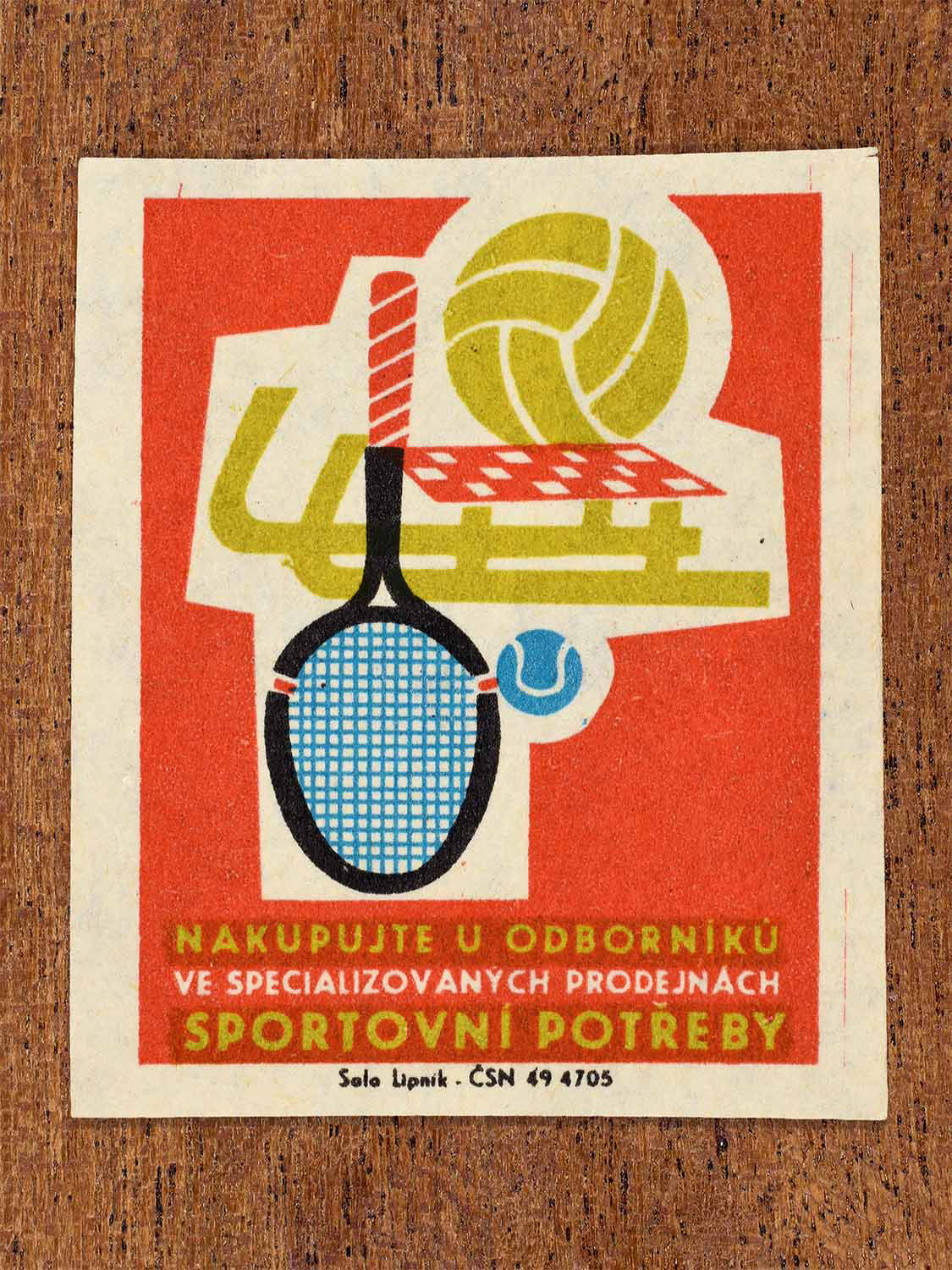 Vintage c. 1967 Czech matchbox label showing a tennis racket, sledge and basket ball in red, blue, yellow and black colours. Produced by the Solo Lipník match factory to promote shopping for sporting goods in specialised retail stores.