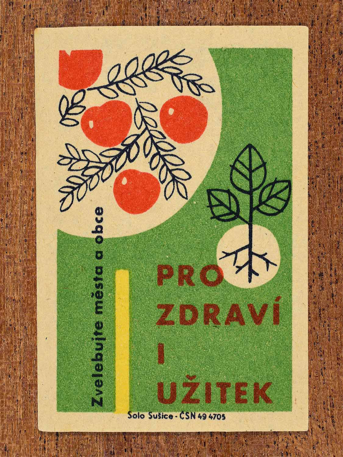 Vintage 1961 Czech matchbox label showing red apples hanging from branches and a young plant sprout with exposed roots, on a green background. Produced by the Solo Sušice match factory to promote growing home orchards and crops for health and utility.