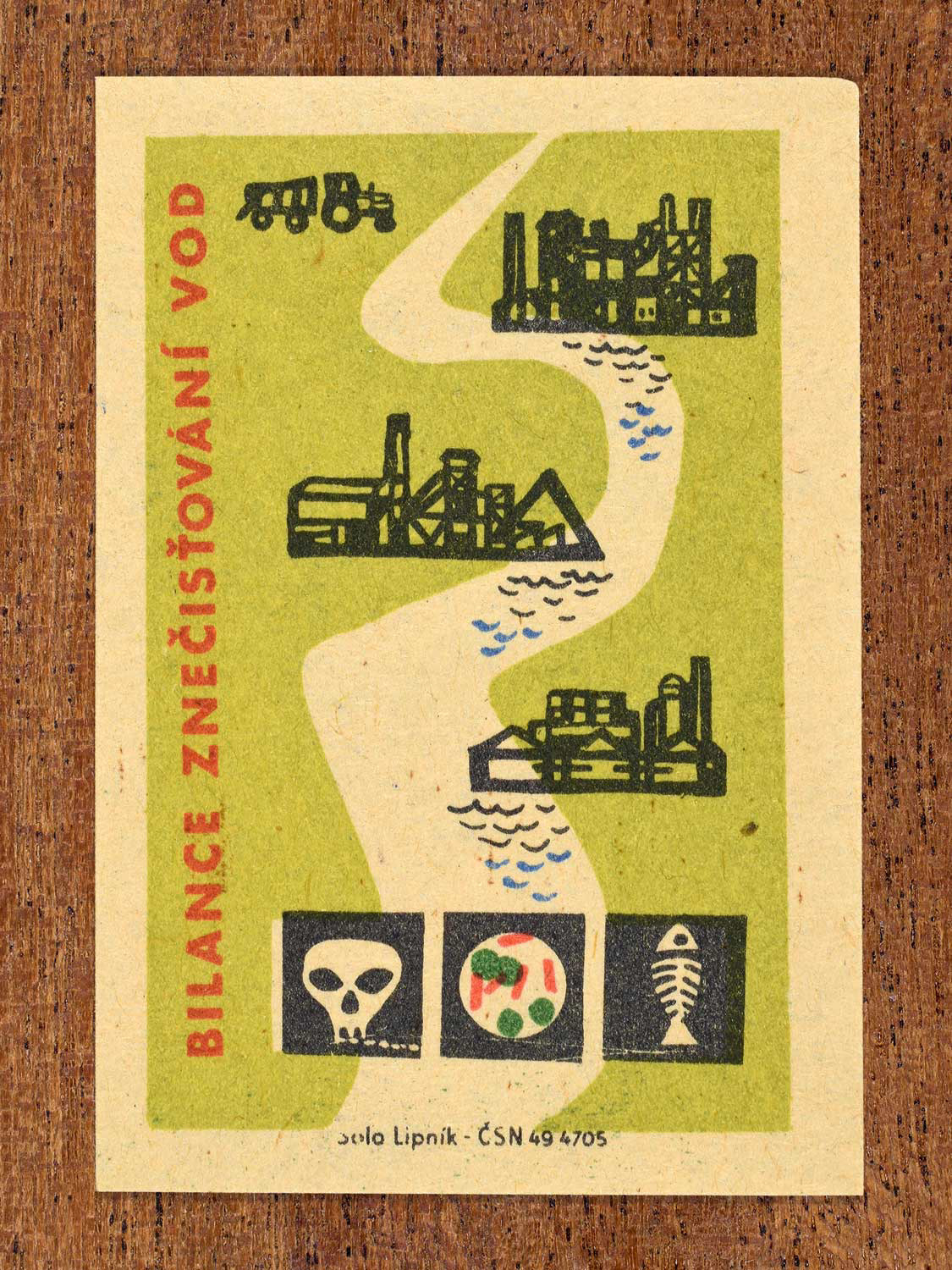 Vintage c. 1963 Czech matchbox label showing a river running through industrial sites with hazard icons, in green, red and black colours. Produced by Solo Lipník match factory warning of toxic water pollution.