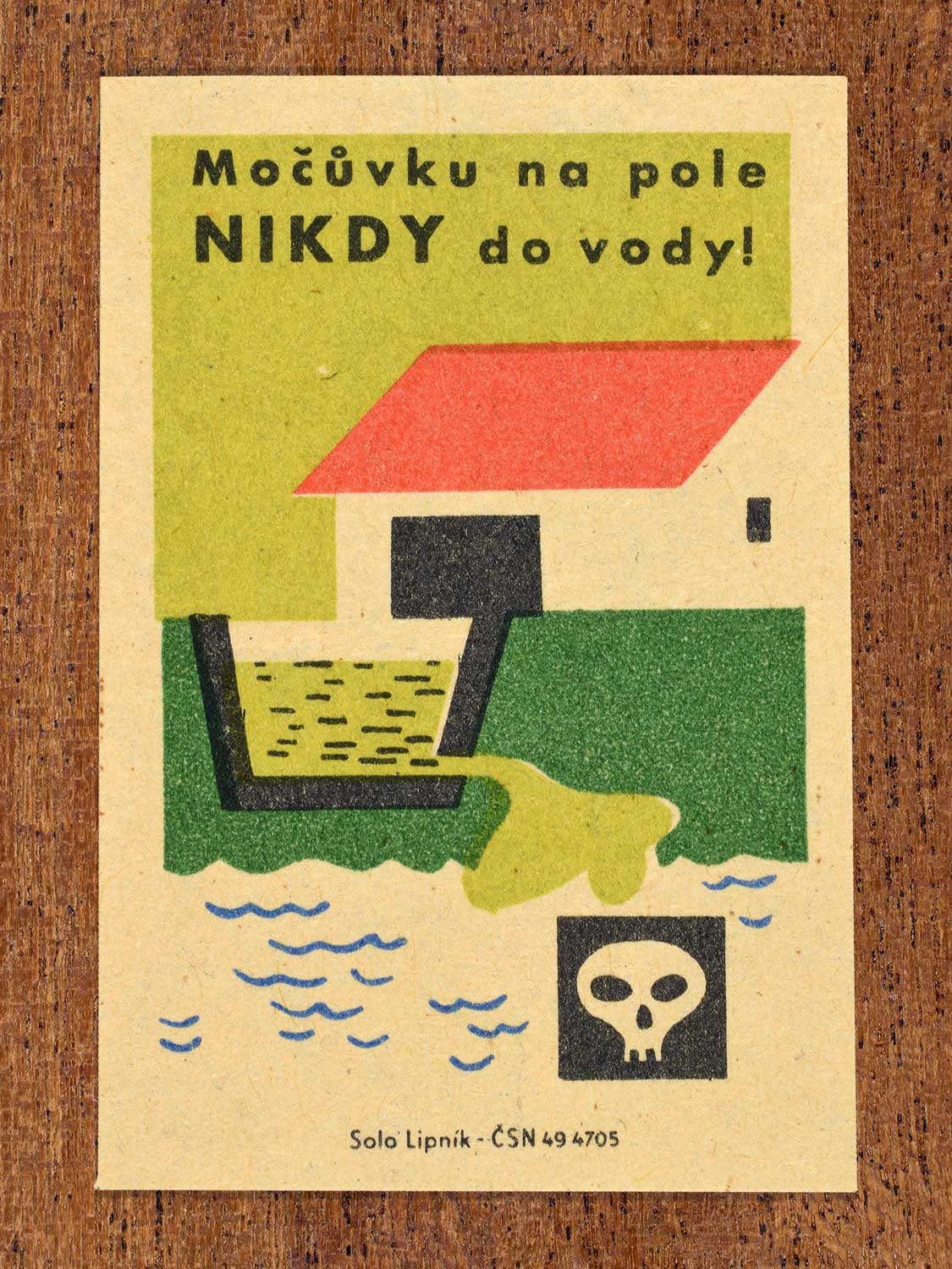 Vintage c. 1963 Czech matchbox label showing liquid manure being dumped into water with warning icons, with green, red and black colours. Produced by Solo Lipník match factory stating that manure belongs on fields and not in water.