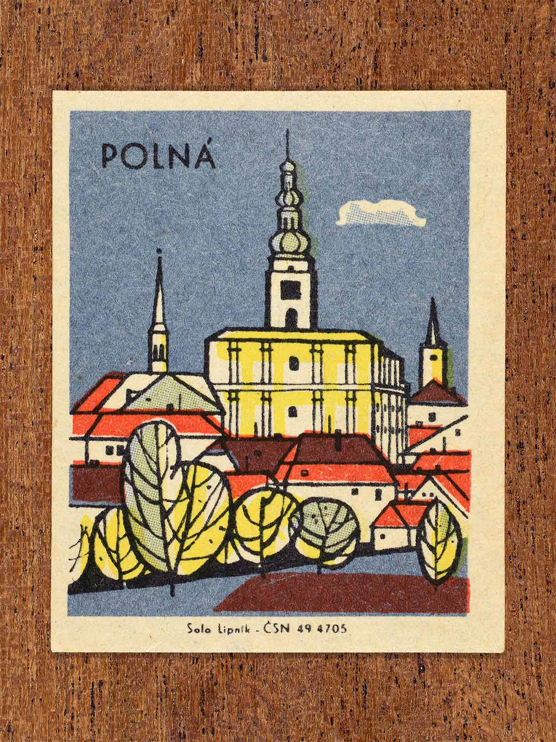 Vintage c. 1967 Czech matchbox label showing a stylised view of Polná with its church and surrounding rooftops in blue, red and yellow colours. Produced by the Solo Lipník match factory to celebrate regional Czechoslovakian towns and architectural heritage.