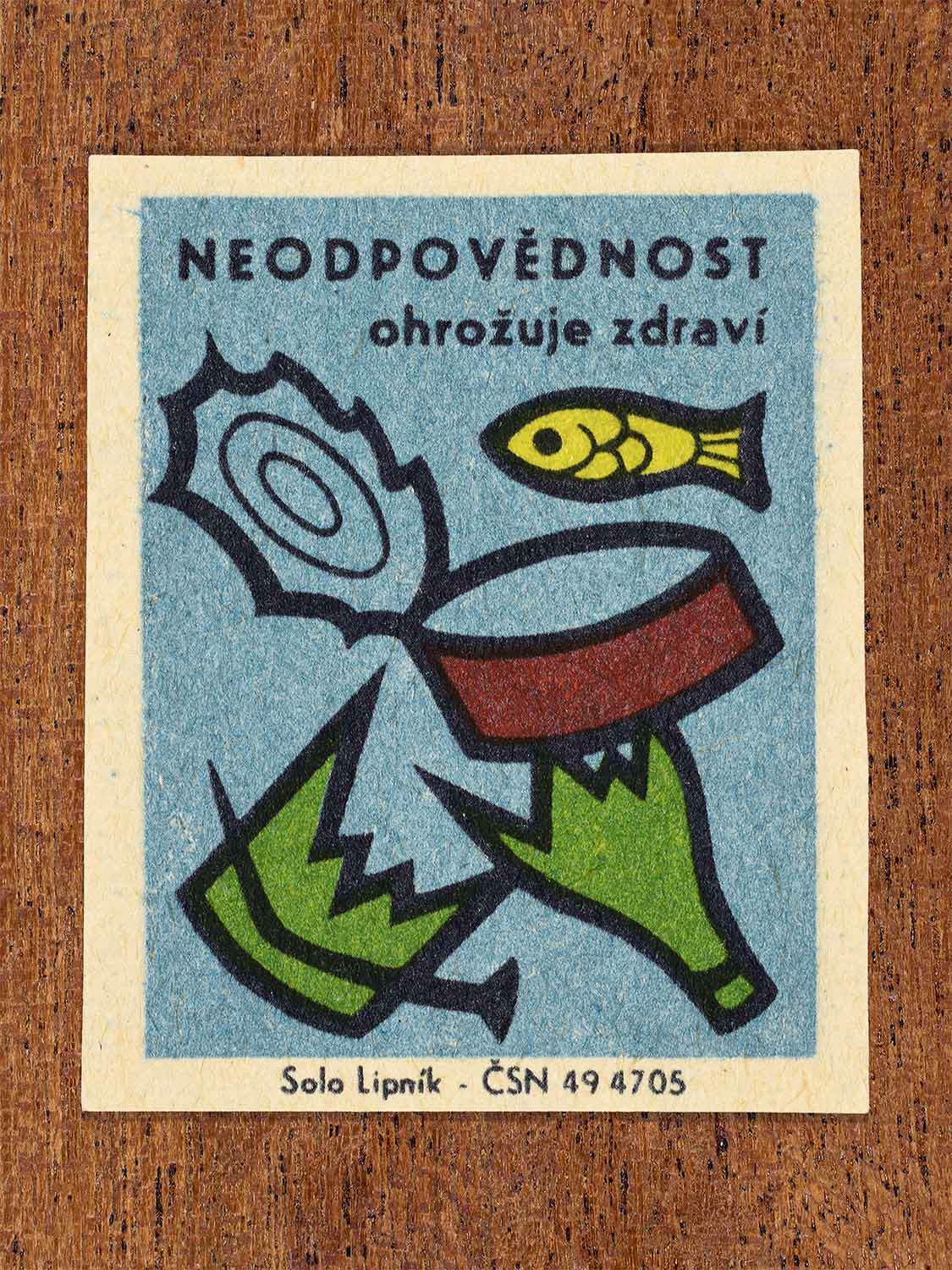 Vintage c. 1966 Czech matchbox label showing polluted water with a dead fish skeleton and a distressed fish in blue, green and yellow colours. Produced by the Solo Lipník match factory to warn that irresponsibility endangers health through water pollution.