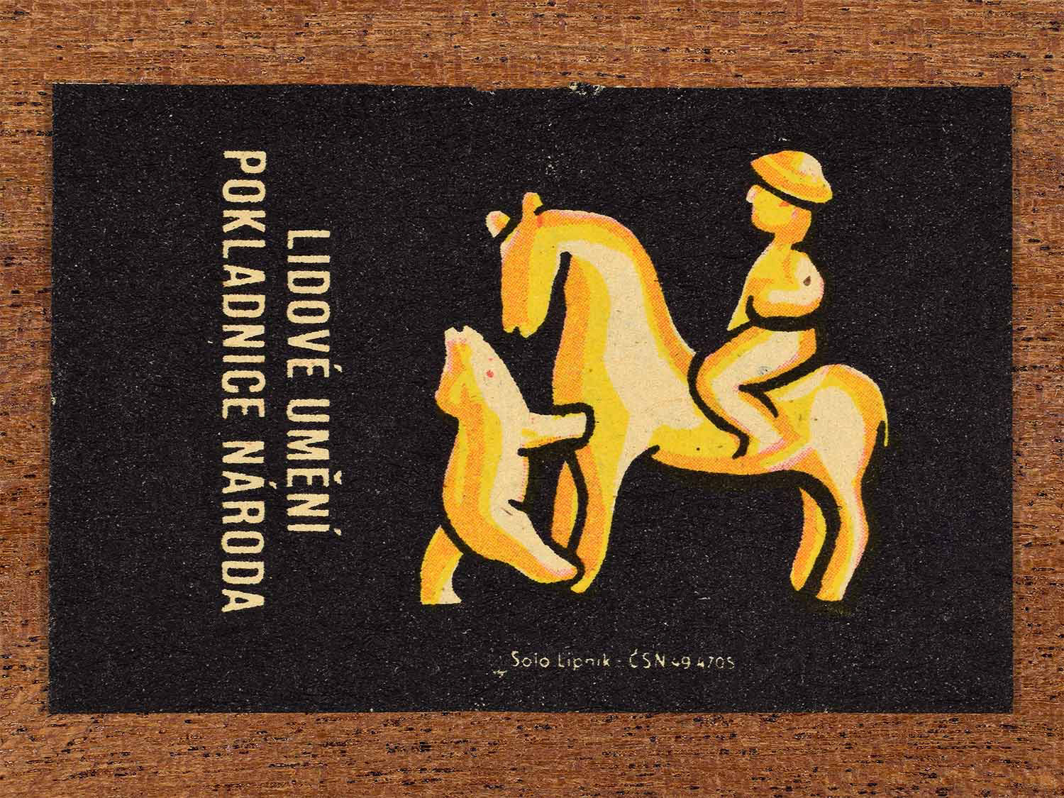 Vintage c. 1962 Czech matchbox label showing a stylised folk ornament in warm yellow and orange tones. Produced by the Solo Lipník match factory to celebrate traditional craft forms.