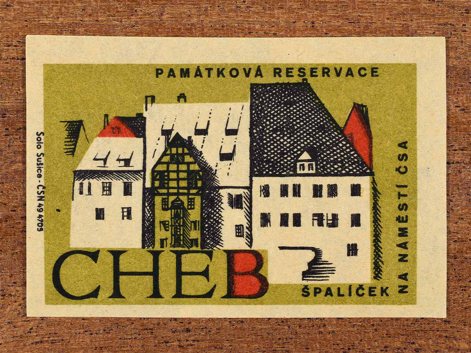 Vintage 1964 Czech matchbox label showing buildings on the Czechoslovak Army Square at Špalíček in Cheb, in olive and red colours. Produced by the Solo Sušice match factory to promote awareness of protected historic monuments.
