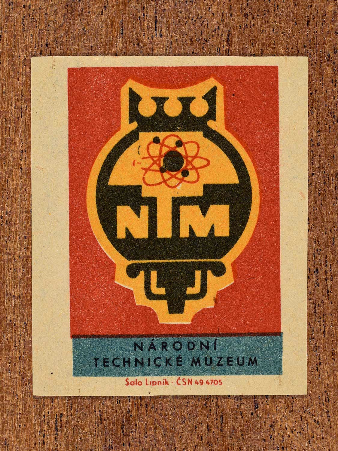 Vintage 1964 Czechoslovakia matchbox label showing an emblem featuring an atomic symbol in black, yellow, teal and red colours. Produced by the Solo Lipník match factory to promote the Národní Technické Muzeum (National Technical Museum) in Czechoslovakia.