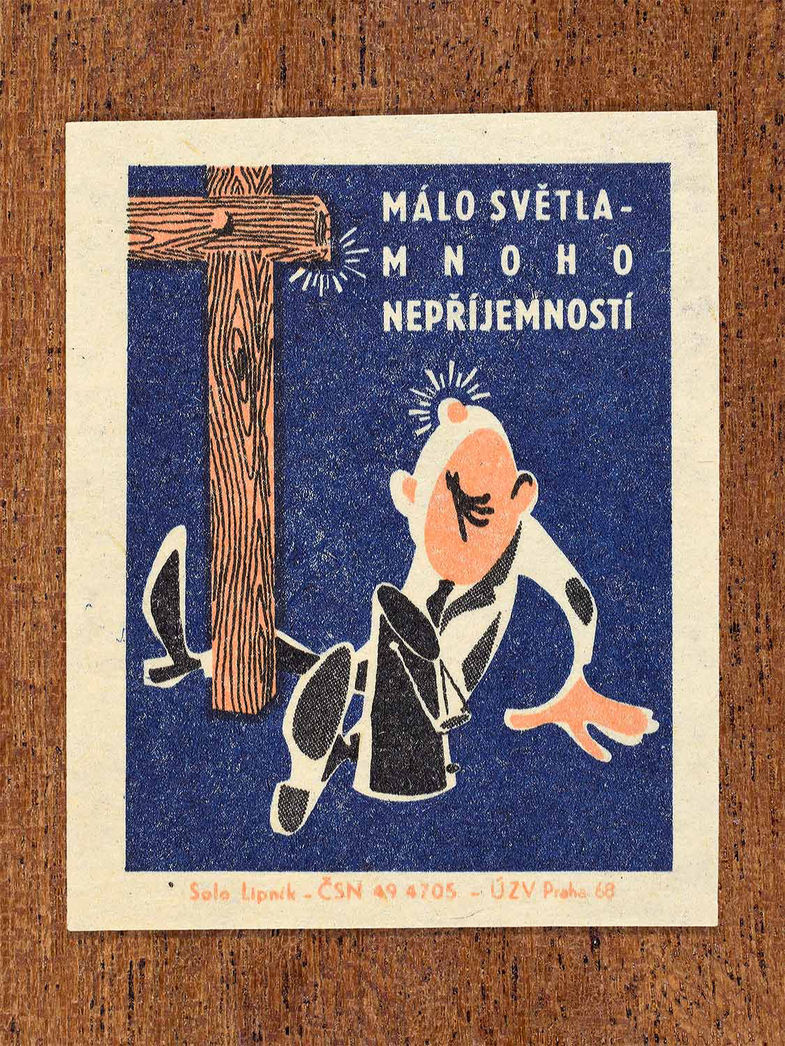 Vintage 1968 Czech matchbox label featuring a cartoon person with a bump on their head sitting next to a wooden post, on blue background. Produced by Solo Lipník match factory to promote proper lighting and maintenance for eye health and safe work practices.