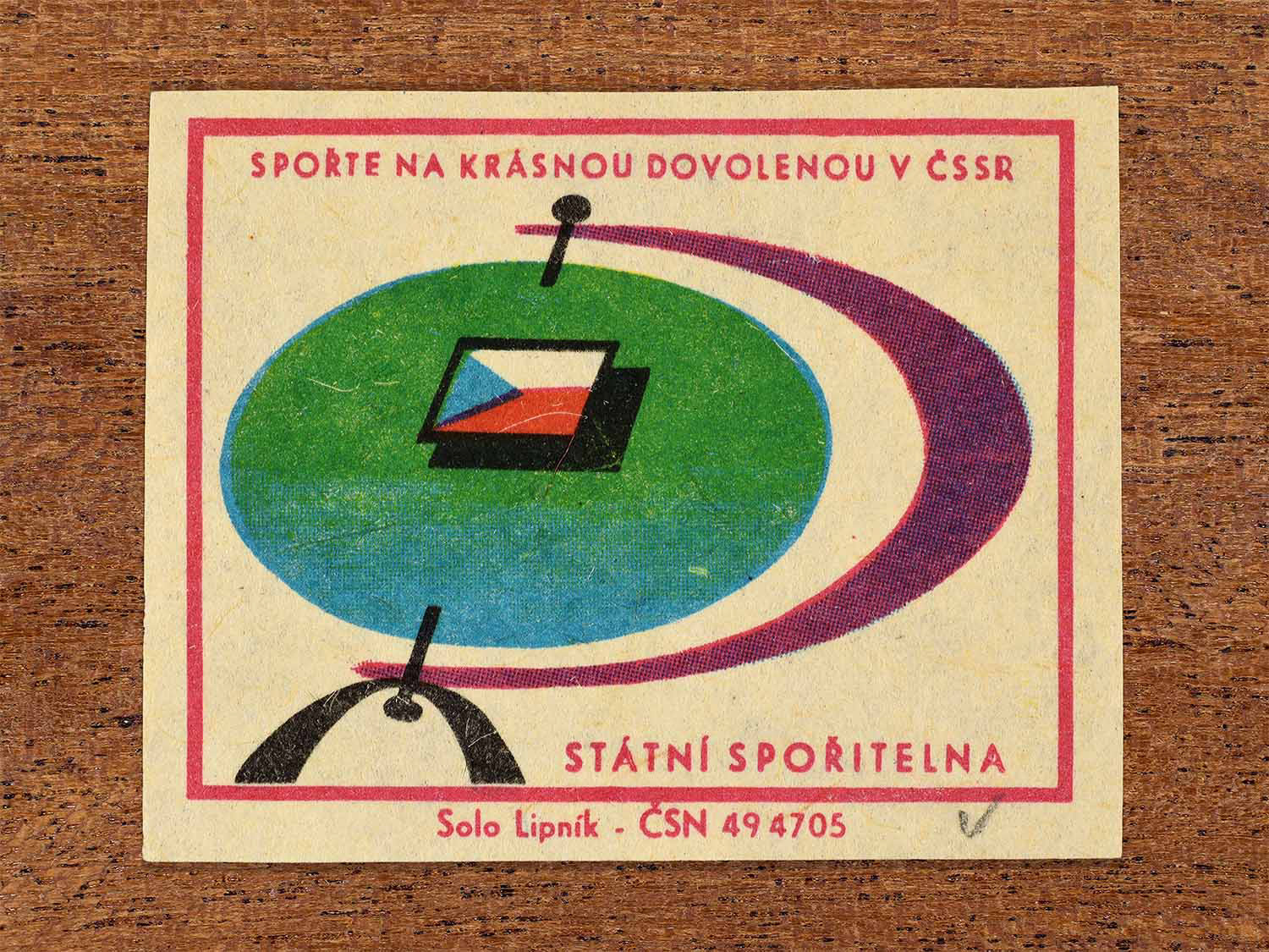 Vintage 1968 Czech matchbox label showing an abstract compass and Czechoslovak flag. Produced by the Solo Lipník match factory to promote saving money for holidays in the Czechoslovak Socialist Republic.