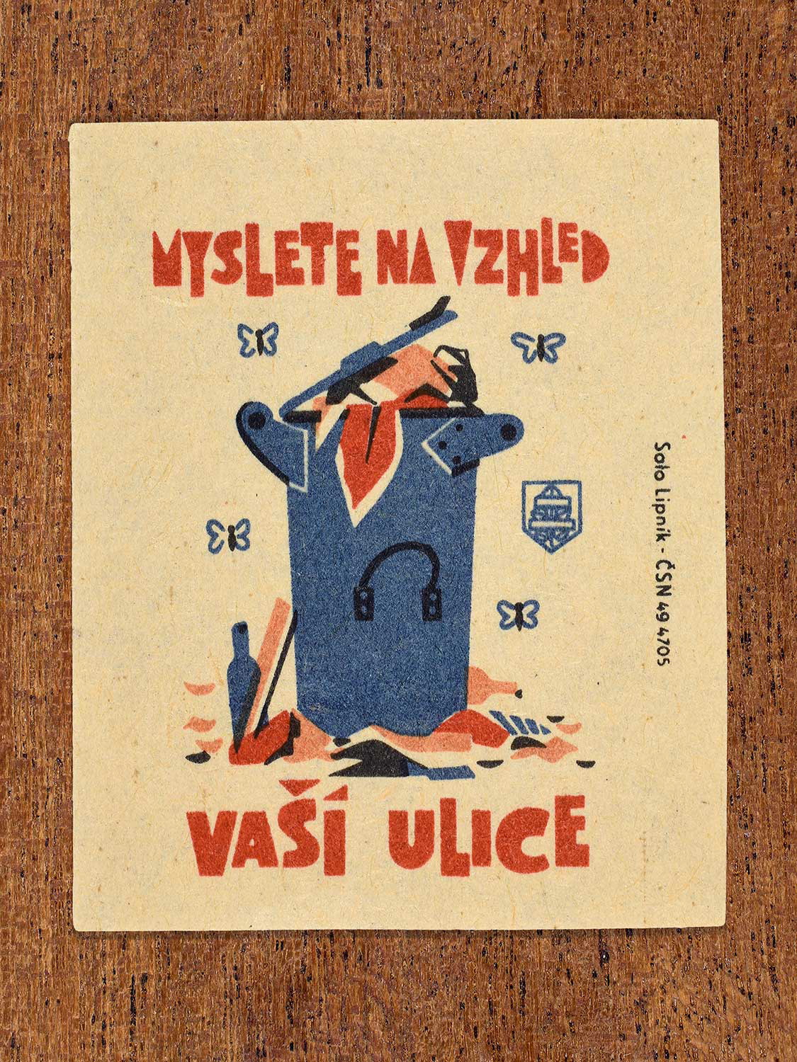 Vintage 1964 Czech matchbox label showing a public litter bin overflowing with rubbish, in blue and red colours. Produced by the Solo Lipník match factory to encourage care for the appearance of public streets.