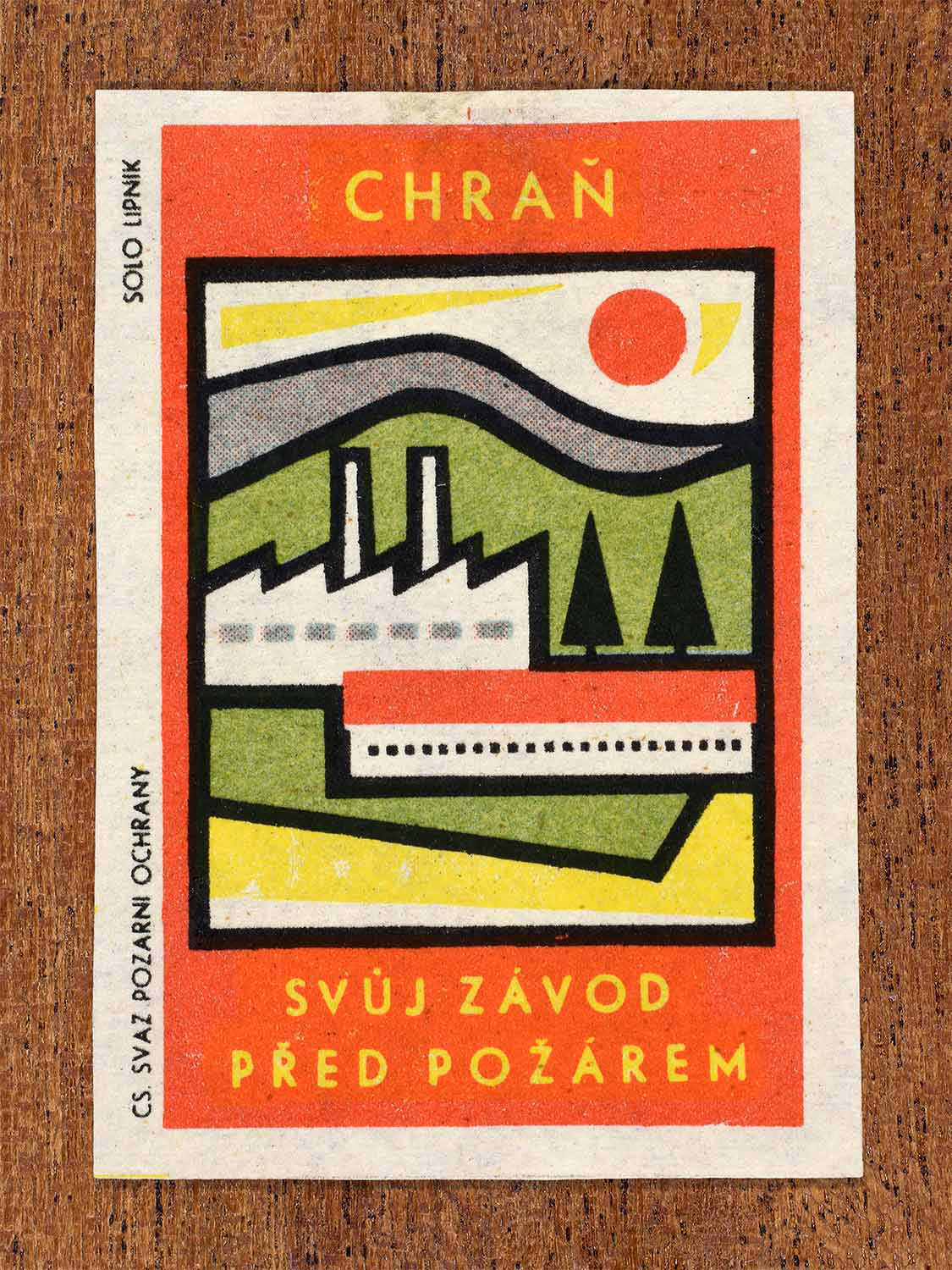 Vintage 1963 Czech matchbox label showing an industrial factory landscape in green, red, yellow and black colours. Produced by the Solo Lipník match factory to encourage fire prevention in workplaces.