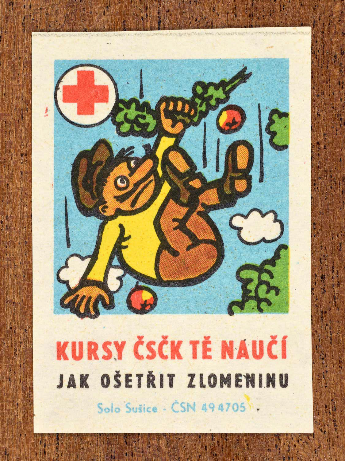 Vintage c. 1966 Czech matchbox label showing a man falling, holding a broken tree branch. Produced by the Solo Sušice match factory to promote first-aid education and correct treatment of fractures in cooperation with the Czechoslovak Red Cross.