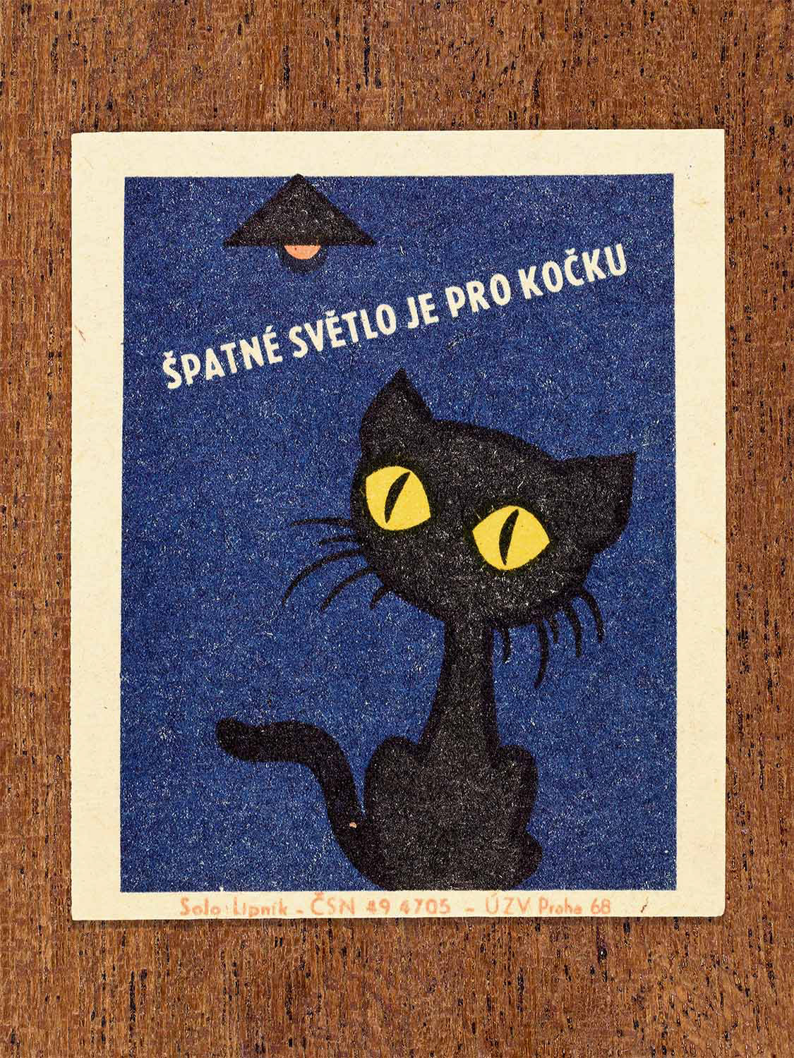 Vintage 1968 Czech matchbox label featuring a cartoon black cat with yellow eyes looking up to a hanging light, on blue background. Produced by Solo Lipník match factory to promote proper lighting and maintenance for eye health and safe work practices.