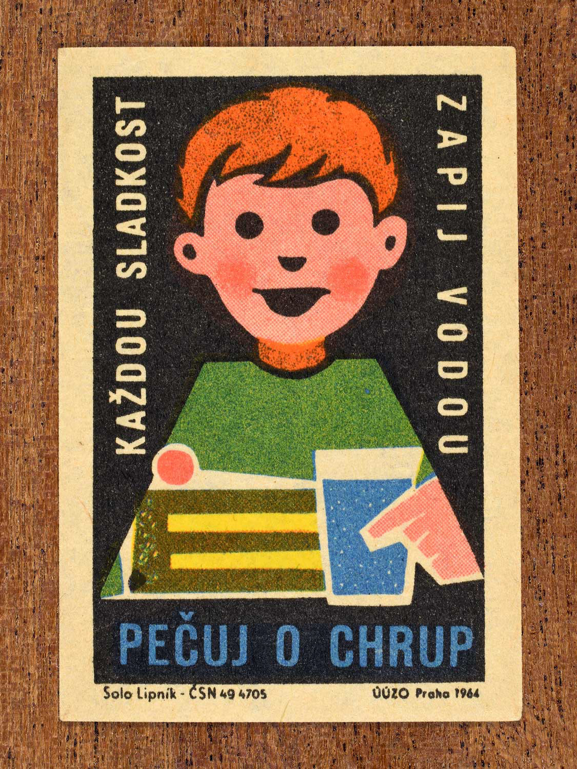 Vintage 1964 Czech matchbox label showing an illustrated child with a piece of cake and glass of water, on a black background. Produced by the Solo Lipník match factory to promote nutrition advice and hygiene habits in protecting healthy teeth.