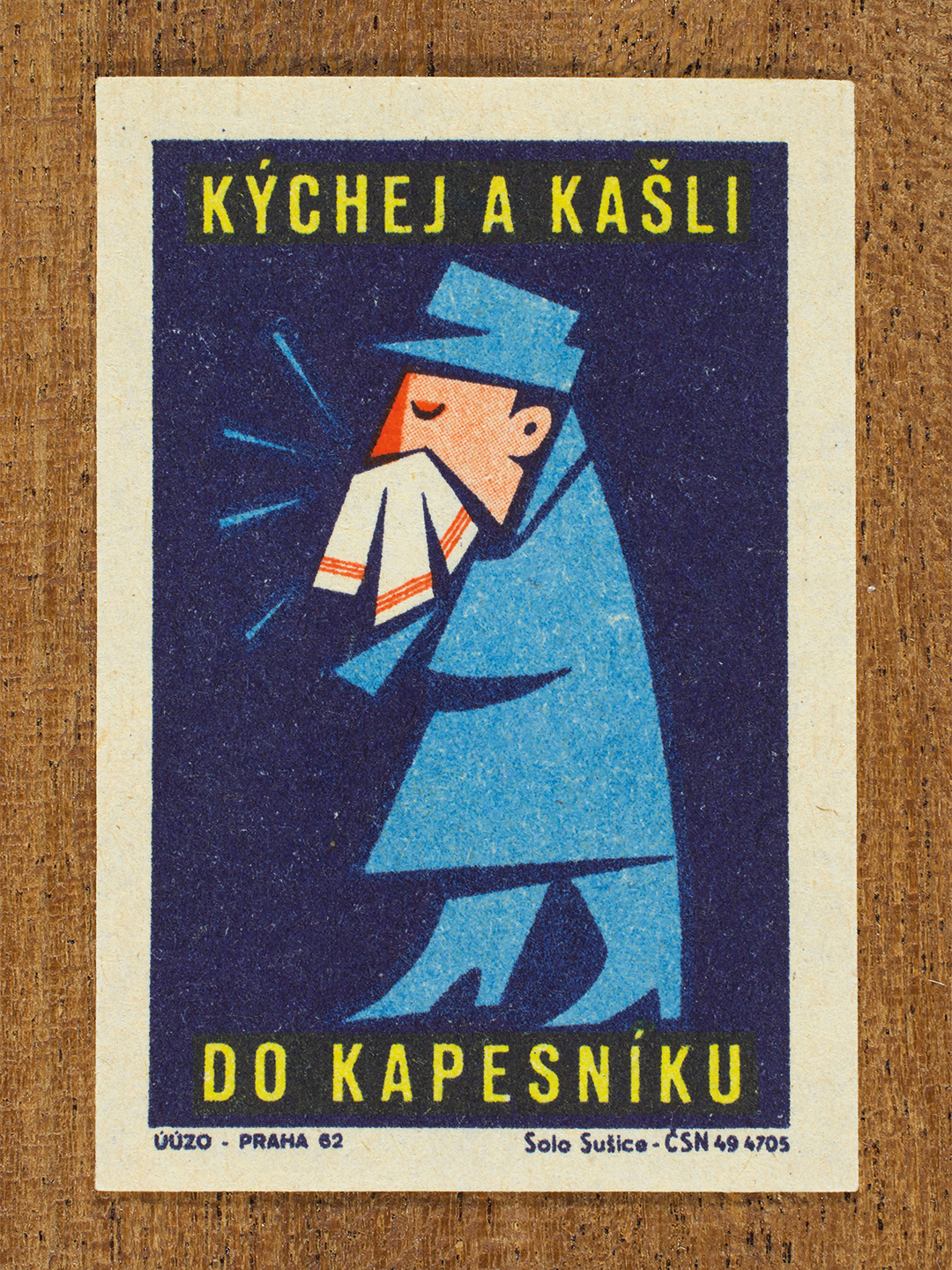 Vintage 1962 Czech matchbox label by Solo Sušice featuring a stylized person sneezing into a handkerchief. Part of the 'Protect Health' series This public-awareness design promotes exercising good manners and preventing the spread of infection.