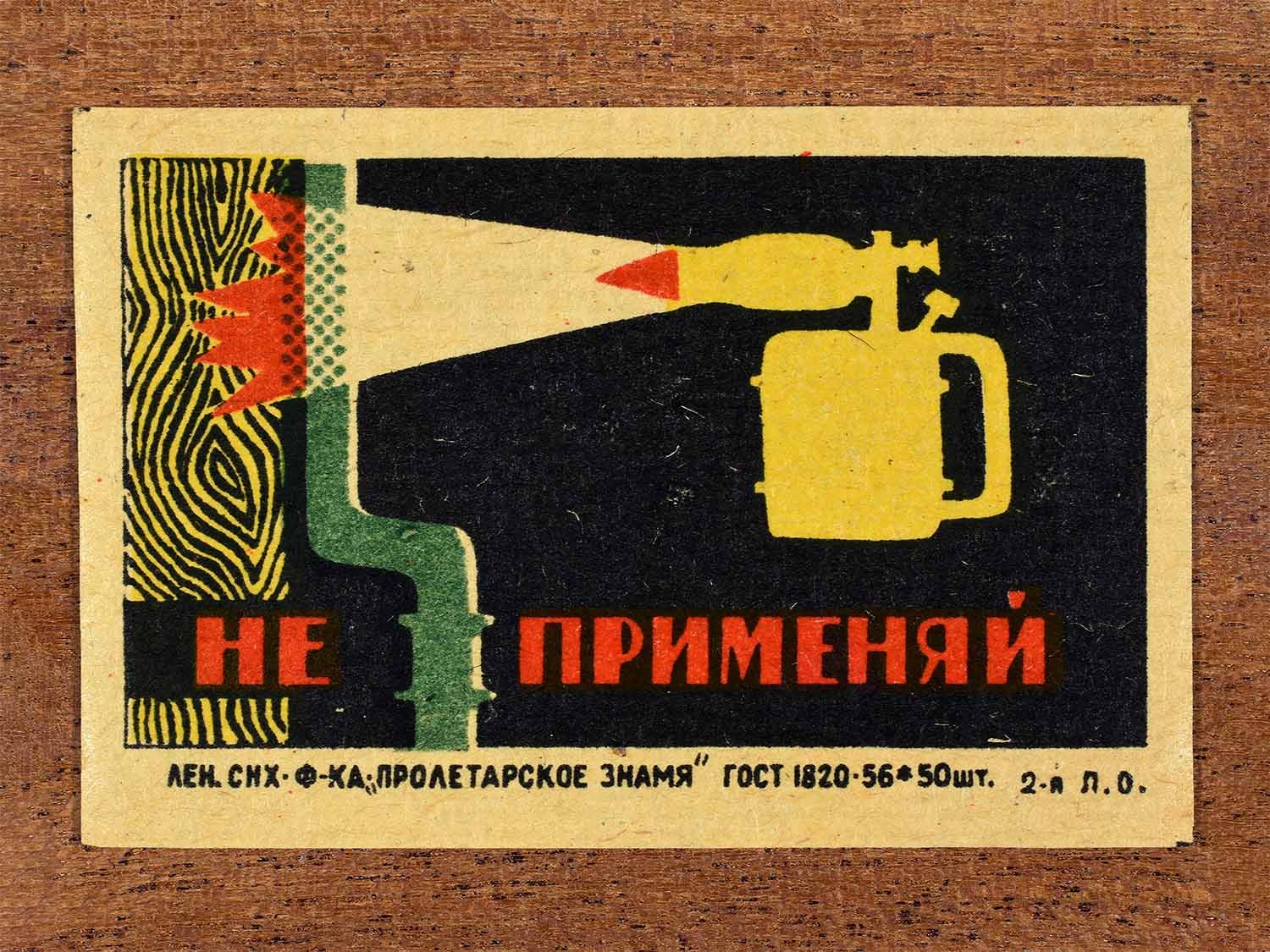 Vintage 1962 Soviet matchbox label showing a blowtorch and pipe in flames. In black, yellow, red and green colours. Produced by the Proletarian Banner match factory to discourage heating of flammable pipe systems.