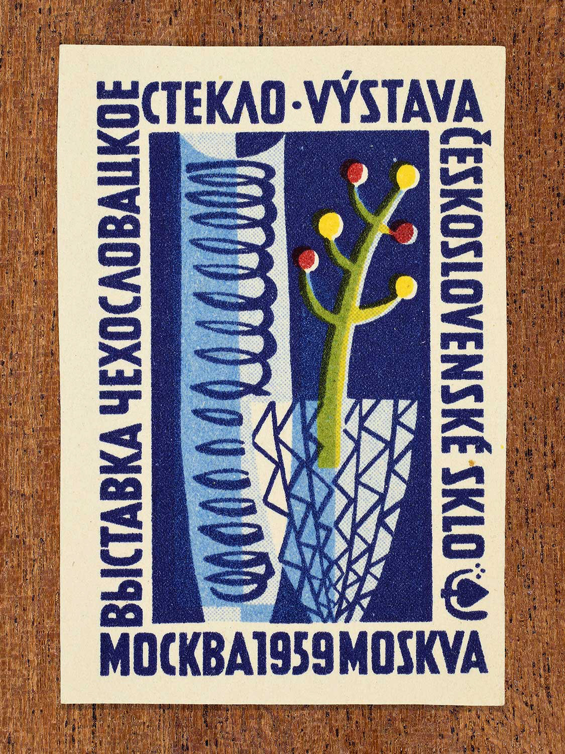 An illustration of two stylised glass vessels on a blue background depicted on a 1959 vintage matchbox label. The design functions to promote an international glass exhibition in Moscow.