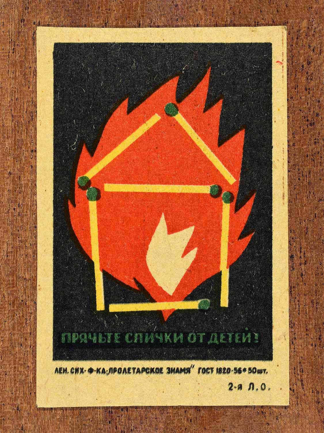 Vintage 1962 Soviet matchbox label showing a house made of matches engulfed in flames, in red, yellow, green and black colours. Produced by the Proletarian Banner match factory to promote keeping matches away from children.