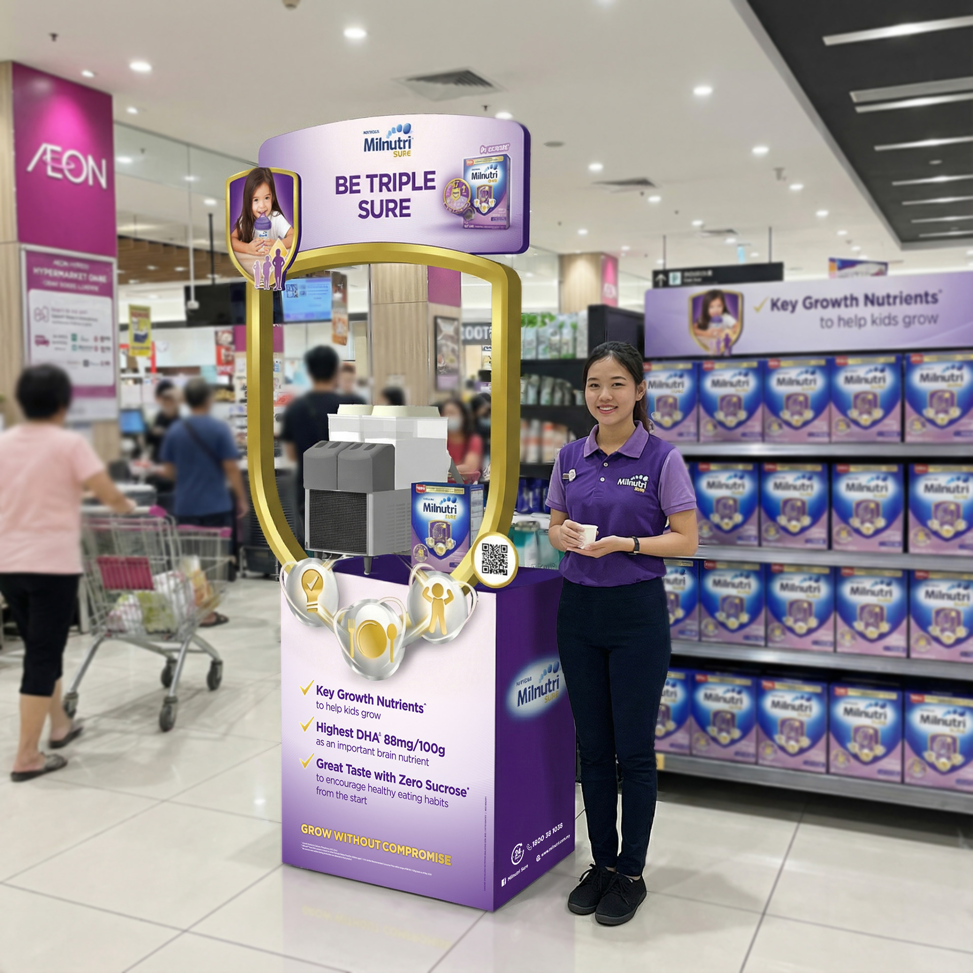 The sampling booth at AEON — uniformed brand promoter, branded dispensing station, sampling cups, and live trial closing the "but will my kid drink it?" objection in the moment.