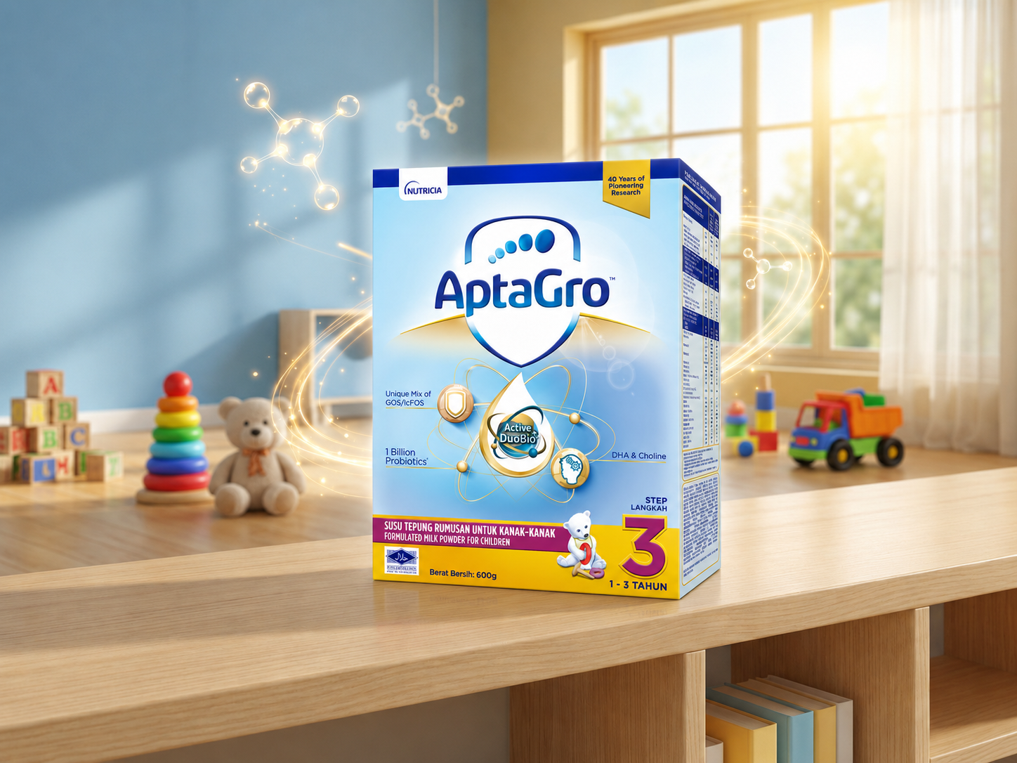 AptaGro Step 3 (1–3 years) growing-up milk carton on a wooden ledge in a softly lit playroom with toys and glowing molecule graphics. The blue-and-gold box shows the Nutricia logo, the AptaGro shield, an atom-like science device around an Active DuoBio+ droplet with GOS/lcFOS, 1 Billion Probiotics and DHA & Choline cues, a "40 Years of Pioneering Research" flash, a polar-bear character, Halal mark and "600g." Danone Nutricia premium children's nutrition packaging design, Malaysia.