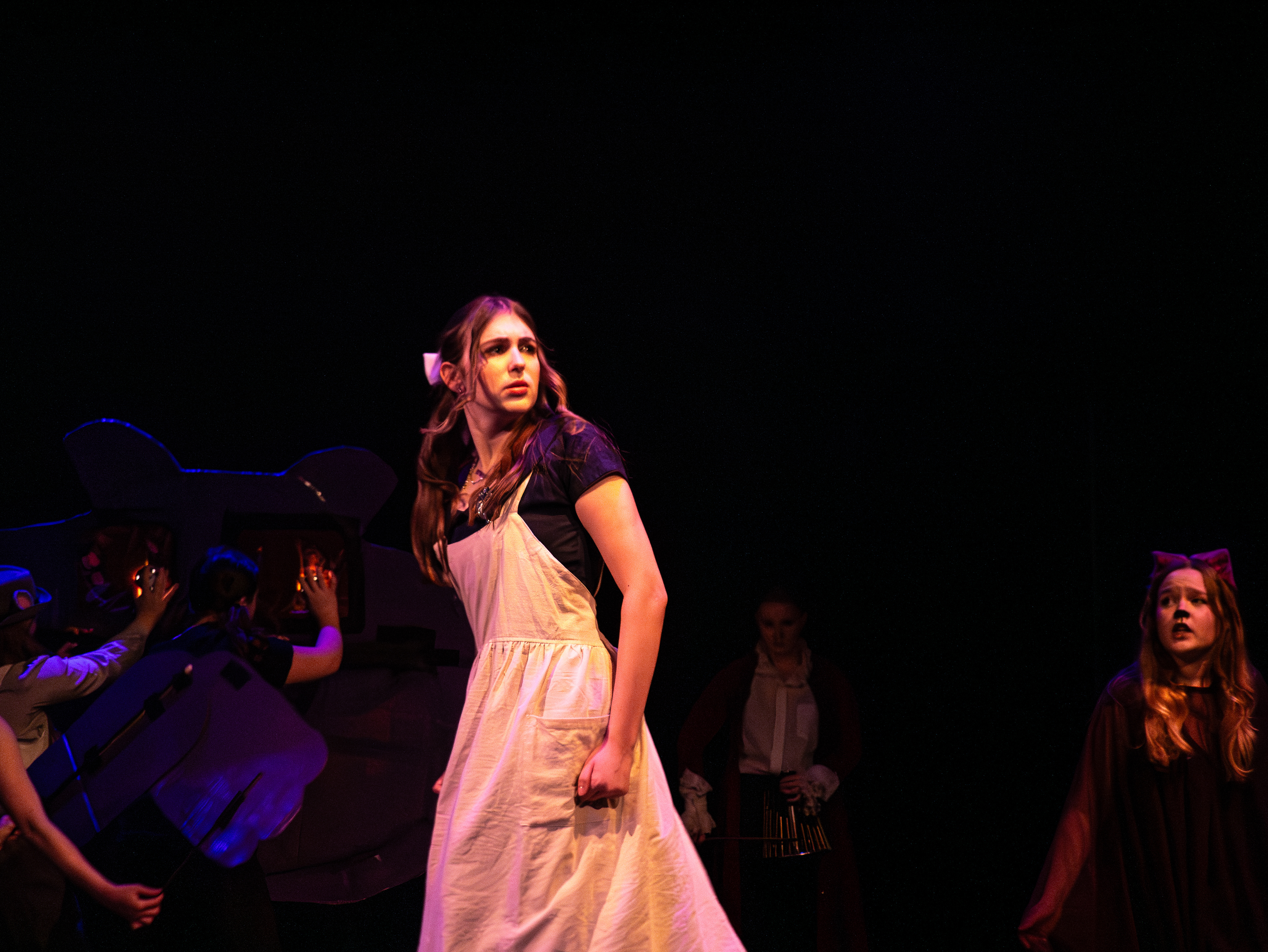 Puppet operators can be seen carrying the Cheshire Cat's head and arm