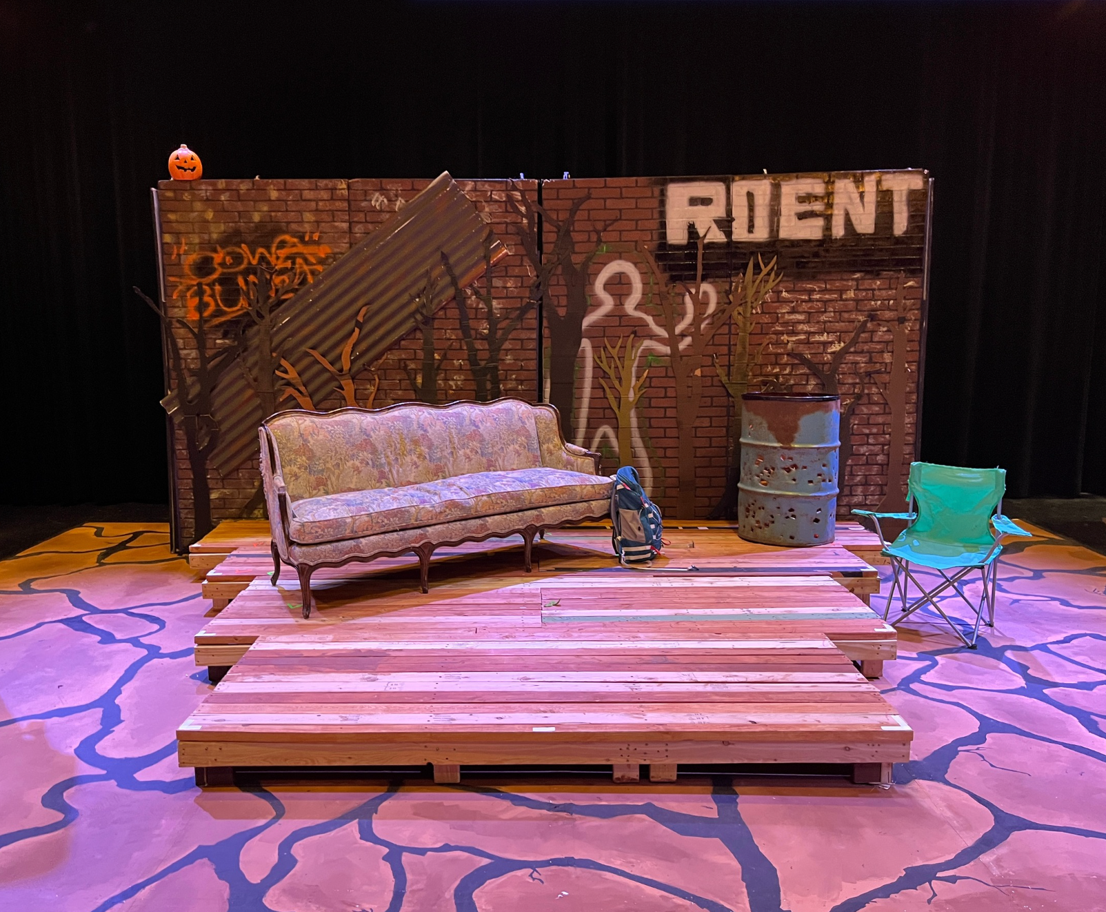Act 1 set, a forest with various mismatched furniture and a dumpster fire
