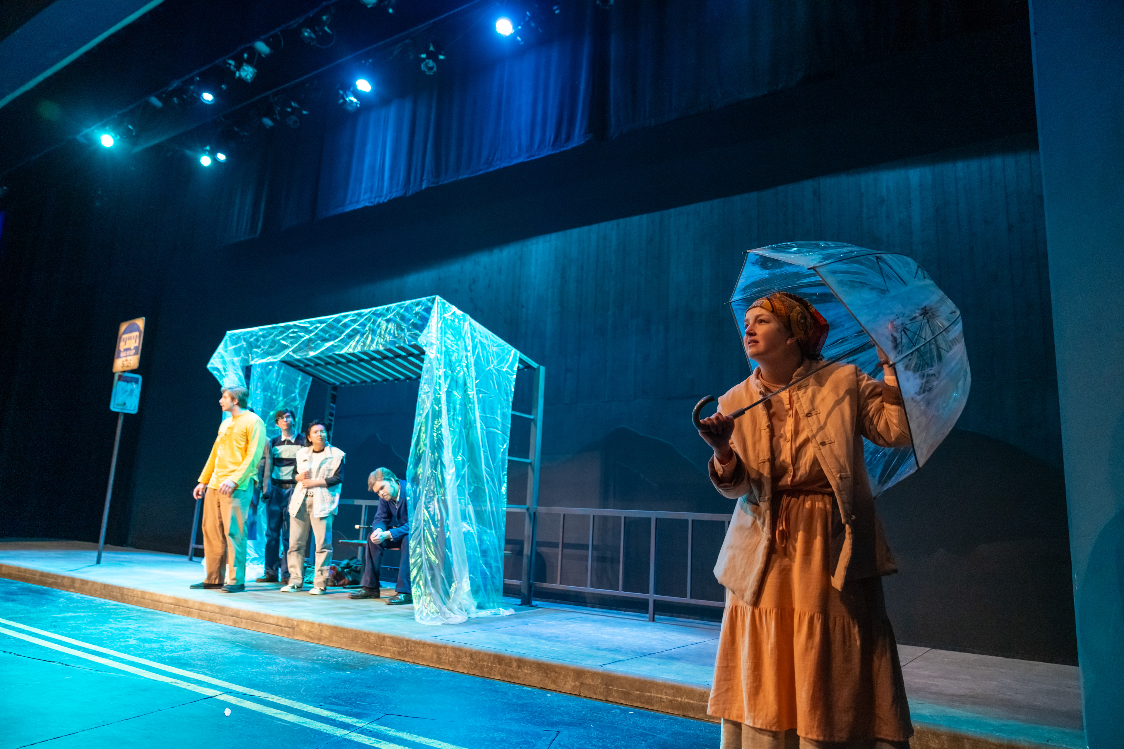 An iridescent fabric sheet and clear umbrella mimic rain in this surrealist play