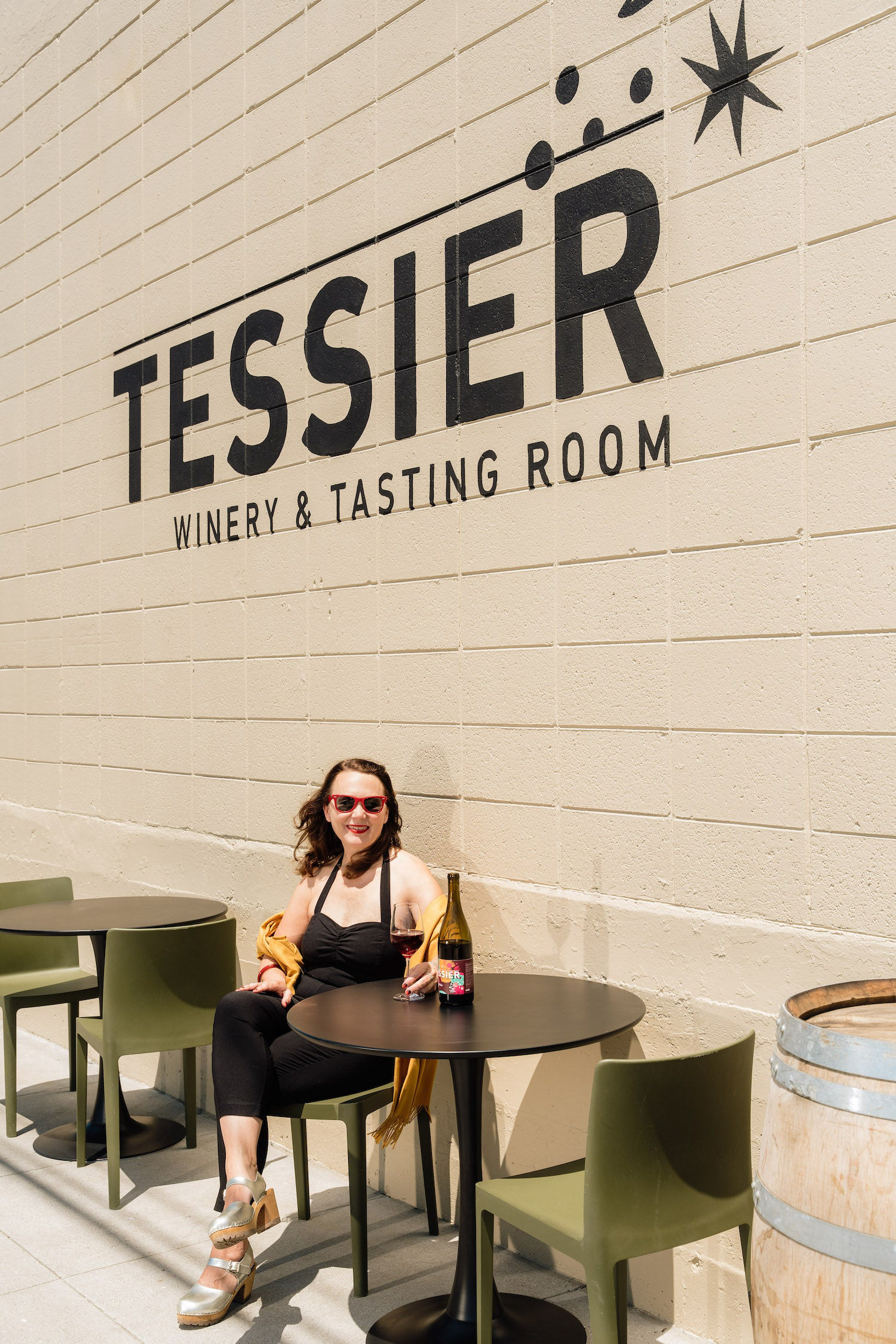 Photo of Tessier Winery outdoor signage and owner sitting at table with wine