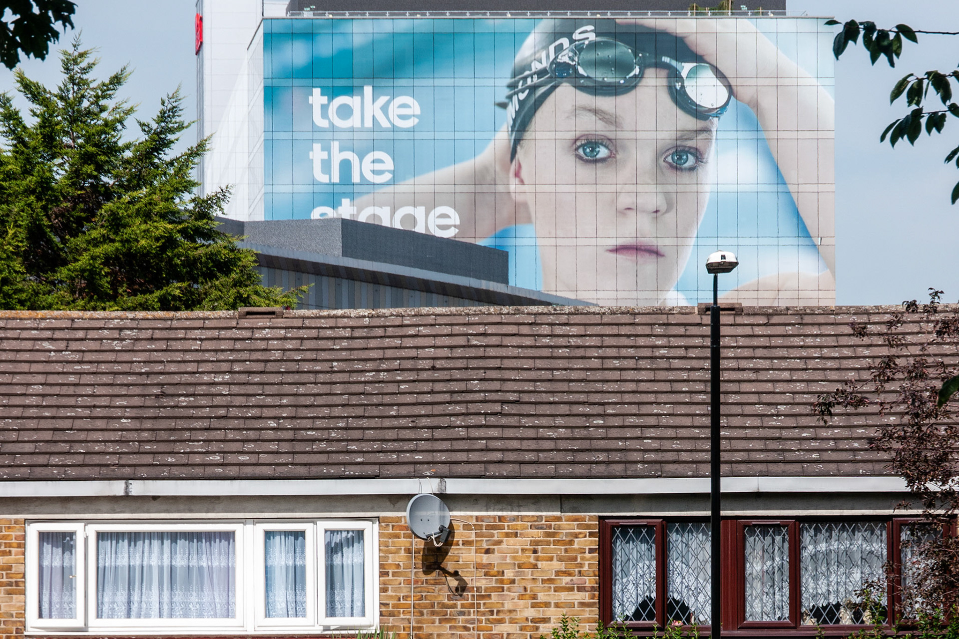 A poster of paralympic swimmer Ellie Simmonds viewed over the roofs of houses on Carpenters Estate: Stratford, London.
