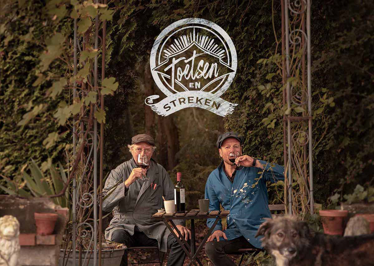 Logo Toetsen en Streken boven foto van Vincent en Wim met een wijnglas